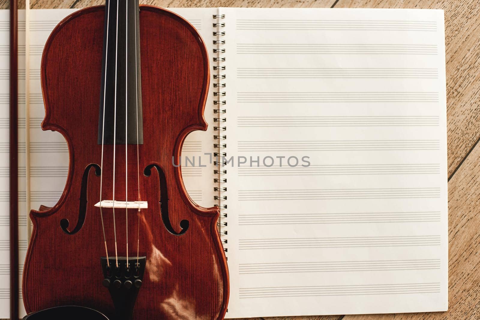 Composing for the violin. Top view of beautiful brown violin lying on sheets for music notes. Violin lessons. Musical instruments. Music equipment.