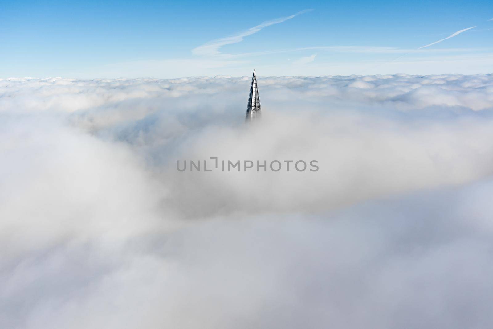 Russia, St. Petersburg, 14 October 2021: The top of the tallest skyscraper in Europe above the clouds, the building of the Gazprom oil company, the spire of a metal and glass structure. High quality photo