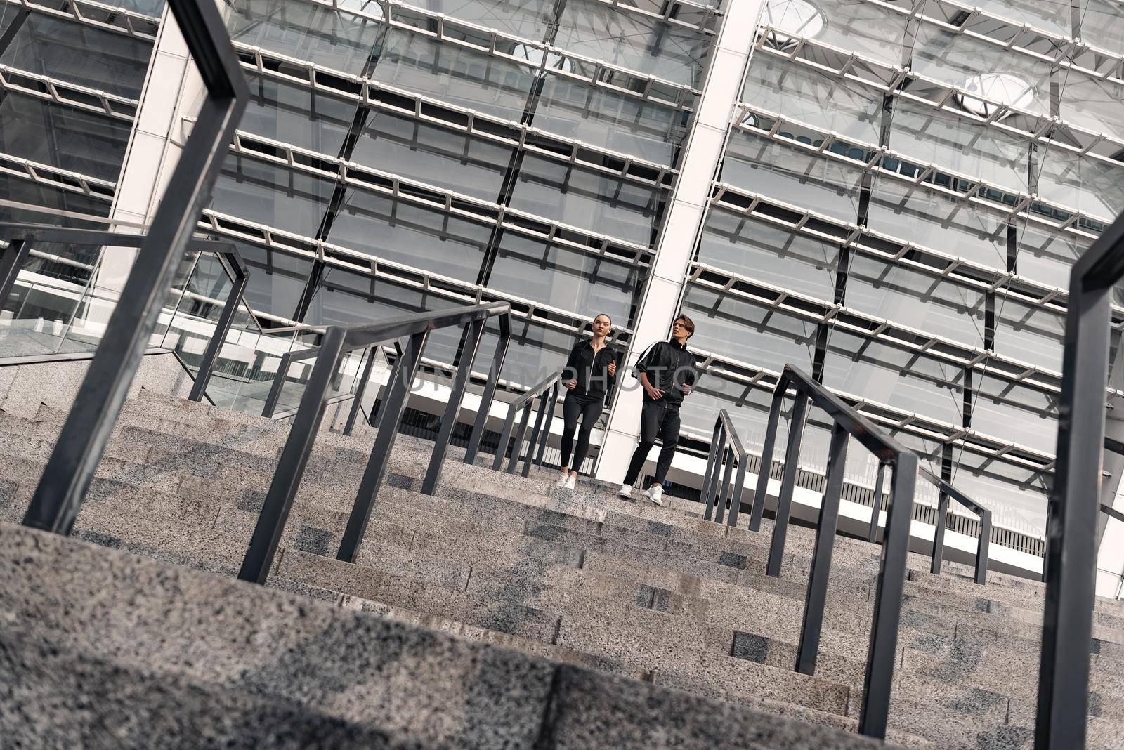 Early morning workout. Young couple running downstairs by friendsstock