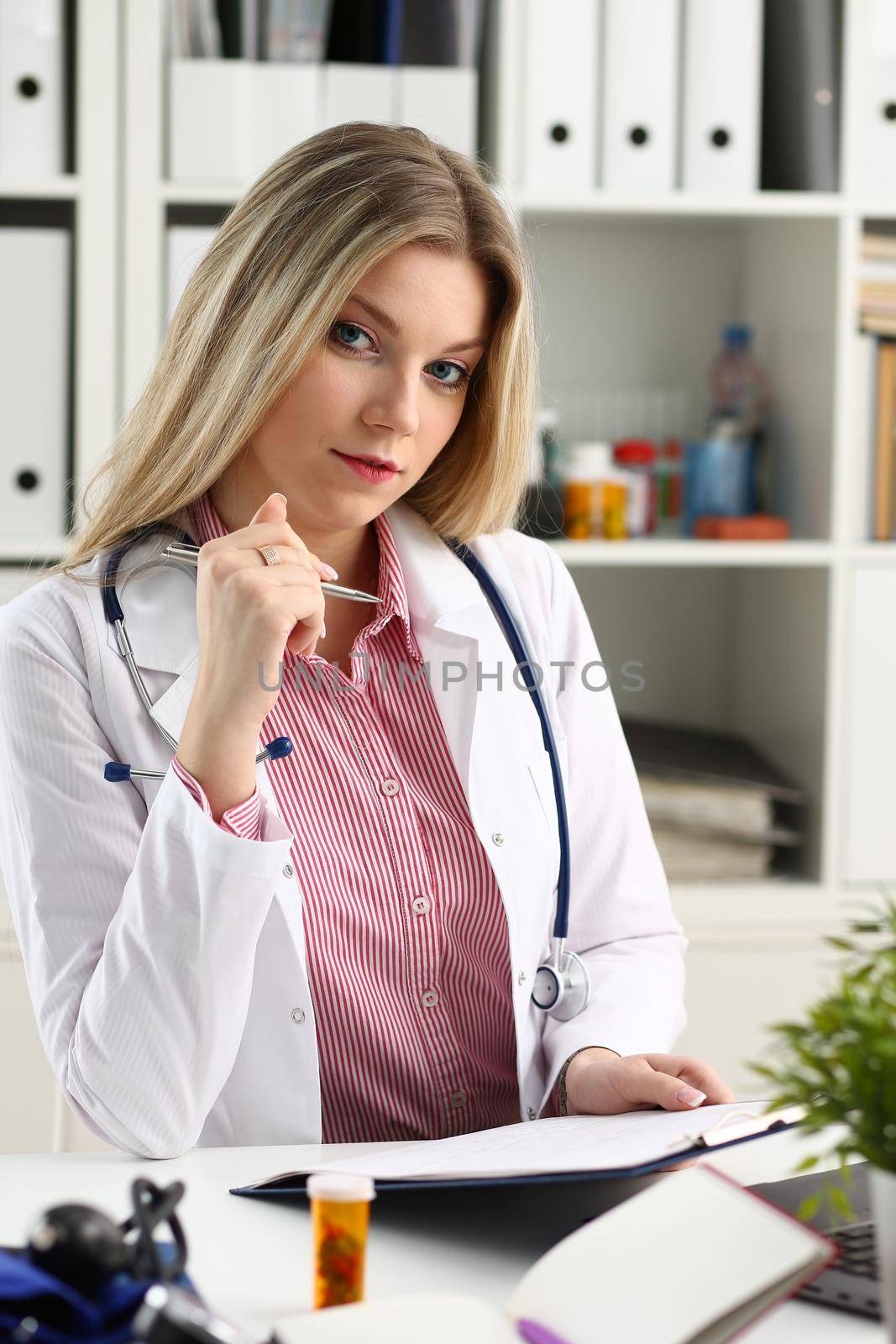 Beautiful smiling female doctor hold clipboard pad and fill something with silver pen. Physical illness prevention prescribe remedy ward round therapeutist assistance healthy lifestyle concept