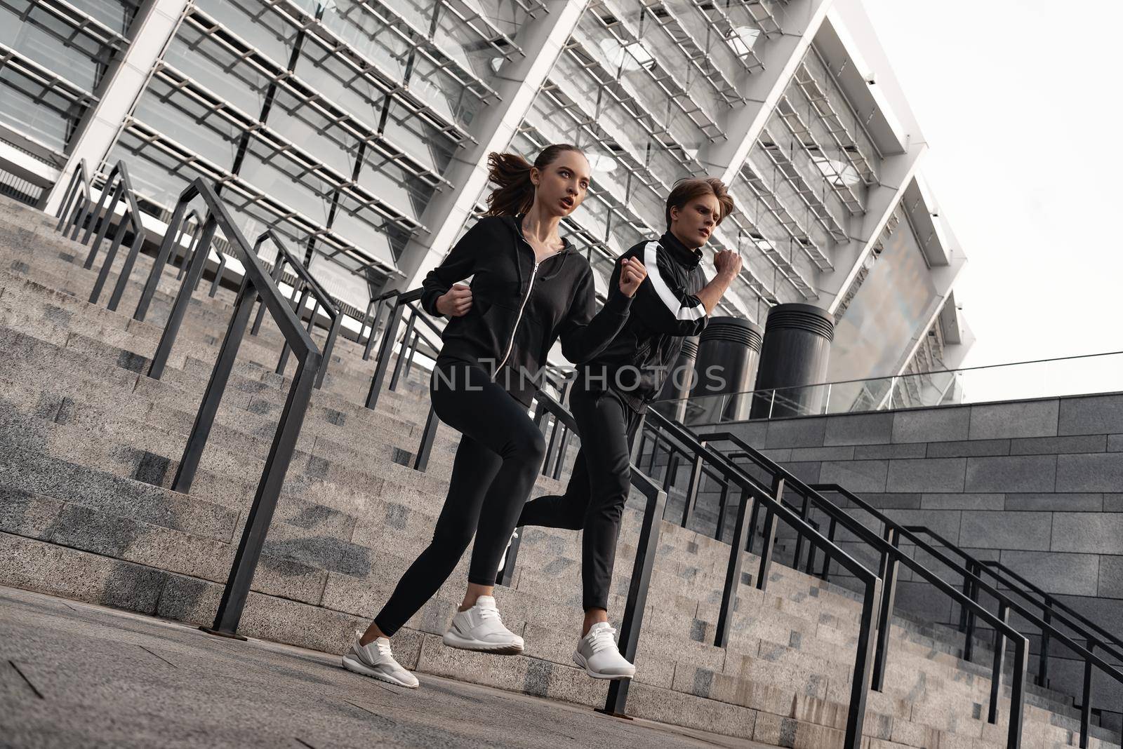 Early morning workout. Young couple running downstairs by friendsstock