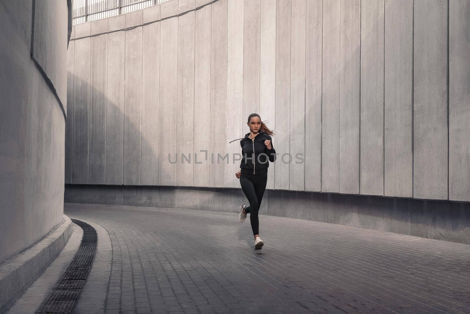 Young athlete is running near the stadium. by friendsstock