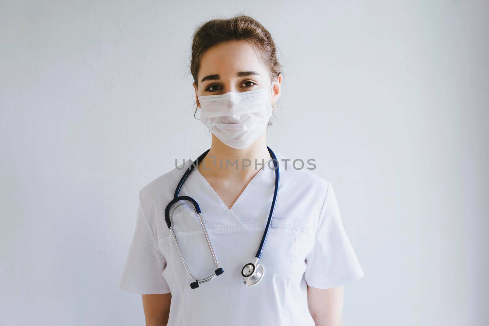 Doctor in a protective disposable mask on his face. A girl in a doctor's uniform. Photo on a medical topic. International Doctor's Day.