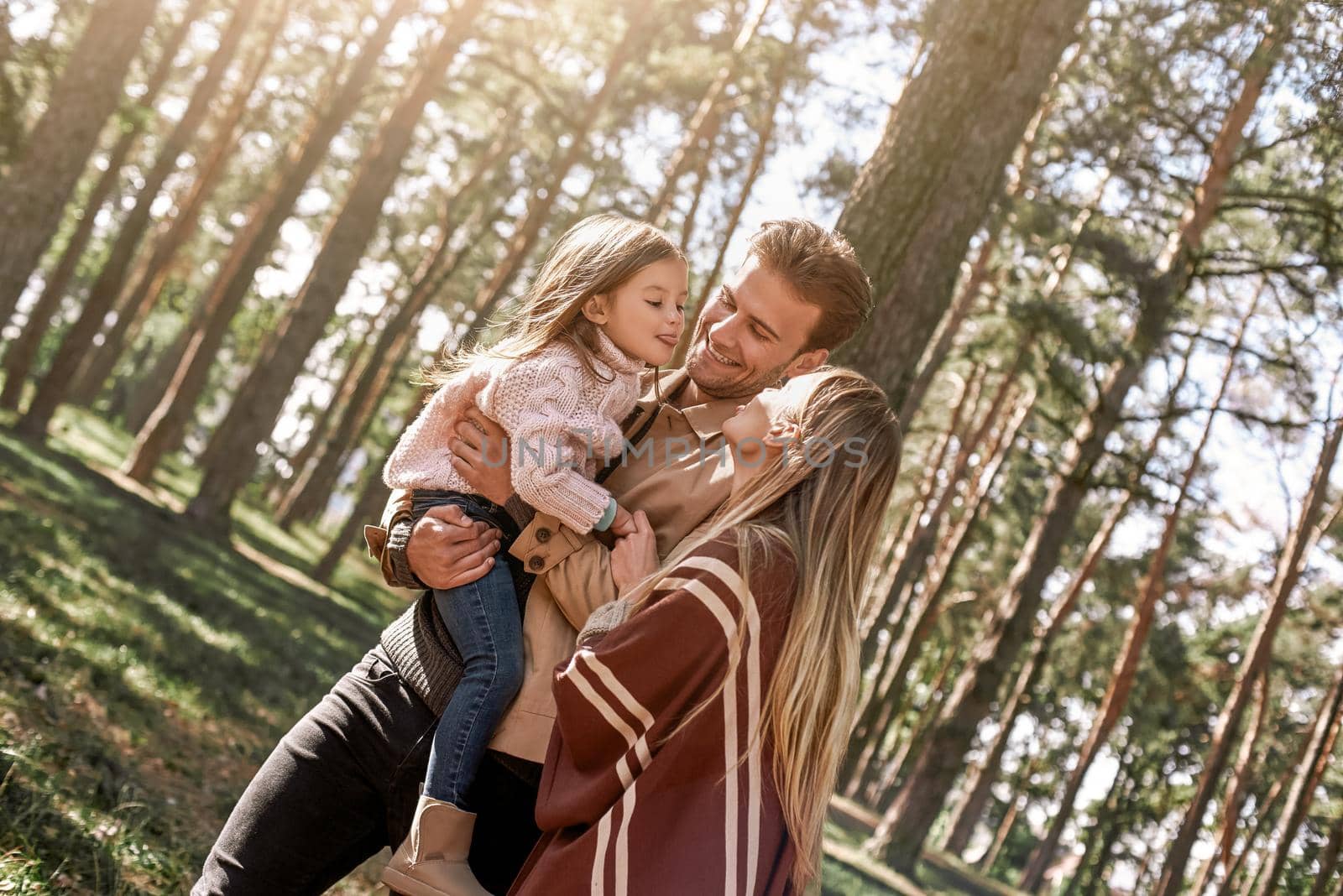 Young parents with little daughter in autumn forest. Close-up by friendsstock