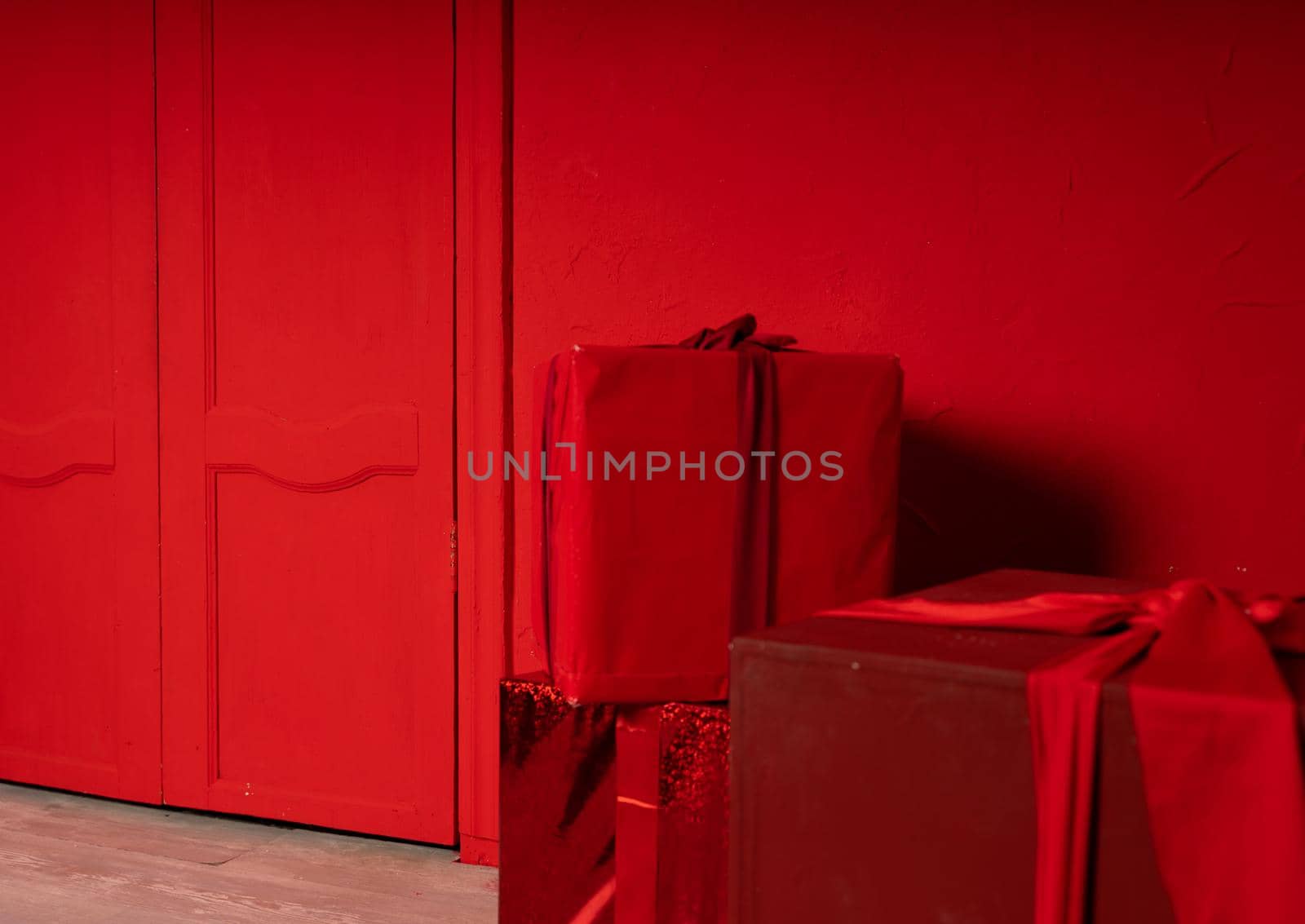 Big wrapped gifts near red wall. Boxes of presents on red background. Concept of holidays and surprises. by epidemiks