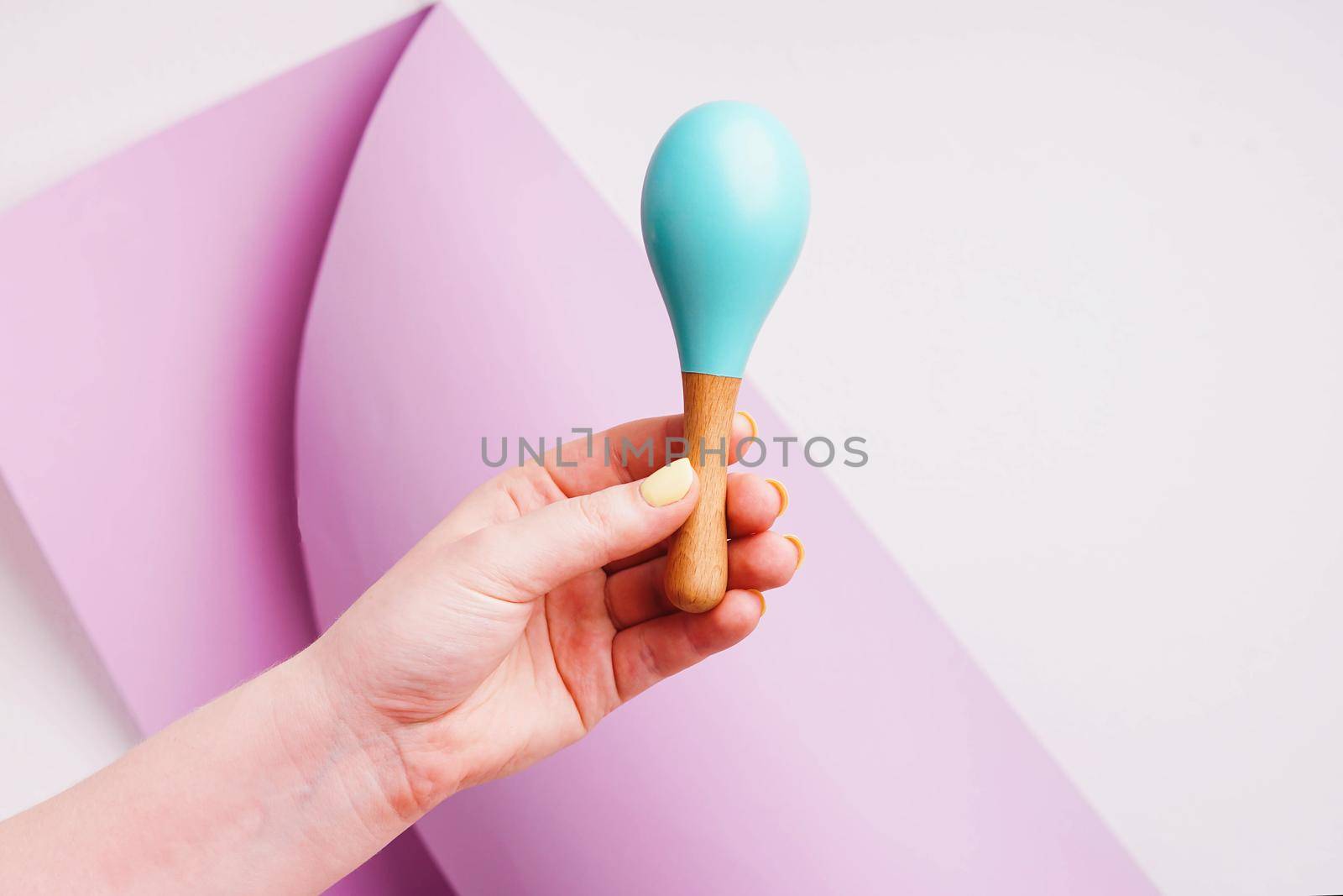 Baby maracas in hand with yellow manicure. Toys made of natural wood. by Rodnova