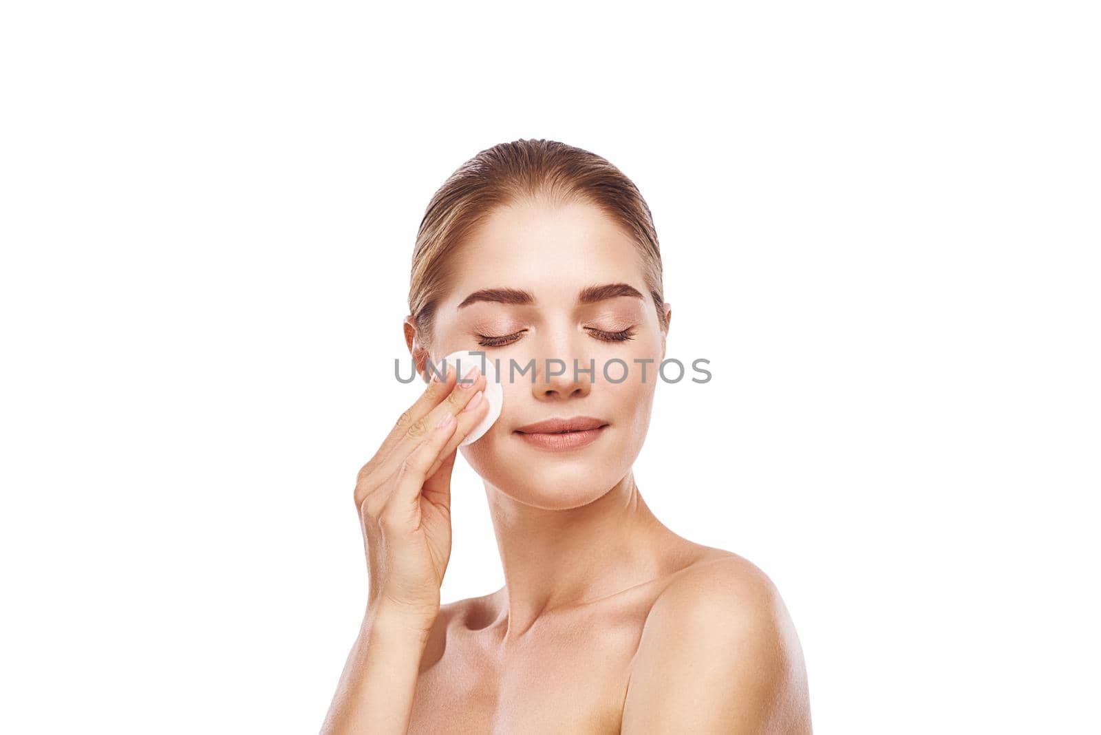 Beautiful woman cleans her face with sponge close-up studio photo on white background. Light hair, grey eyes