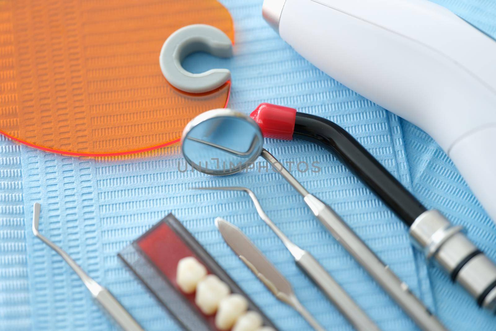 Dental instruments and denture lie on a blue medical napkin, close-up. Sterile instruments for jaw prosthetics. Ceramic tooth implant