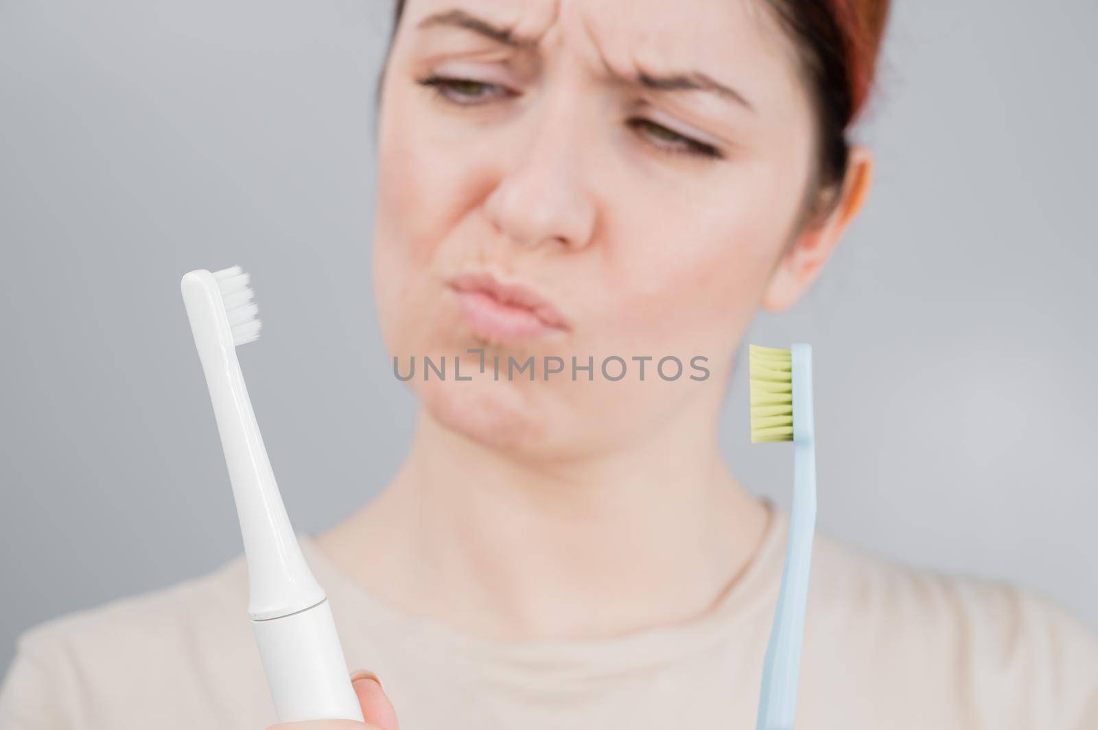 Happy woman compares a toothbrush with an electric one. The girl chooses oral hygiene products by mrwed54