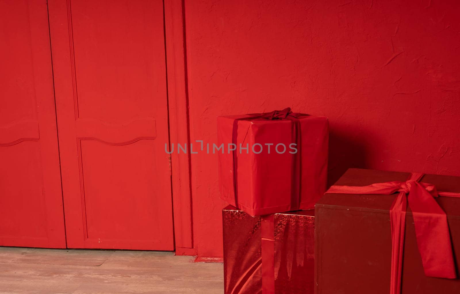 Big wrapped gifts near red wall. Boxes of presents on red background. Concept of holidays and surprises. by epidemiks