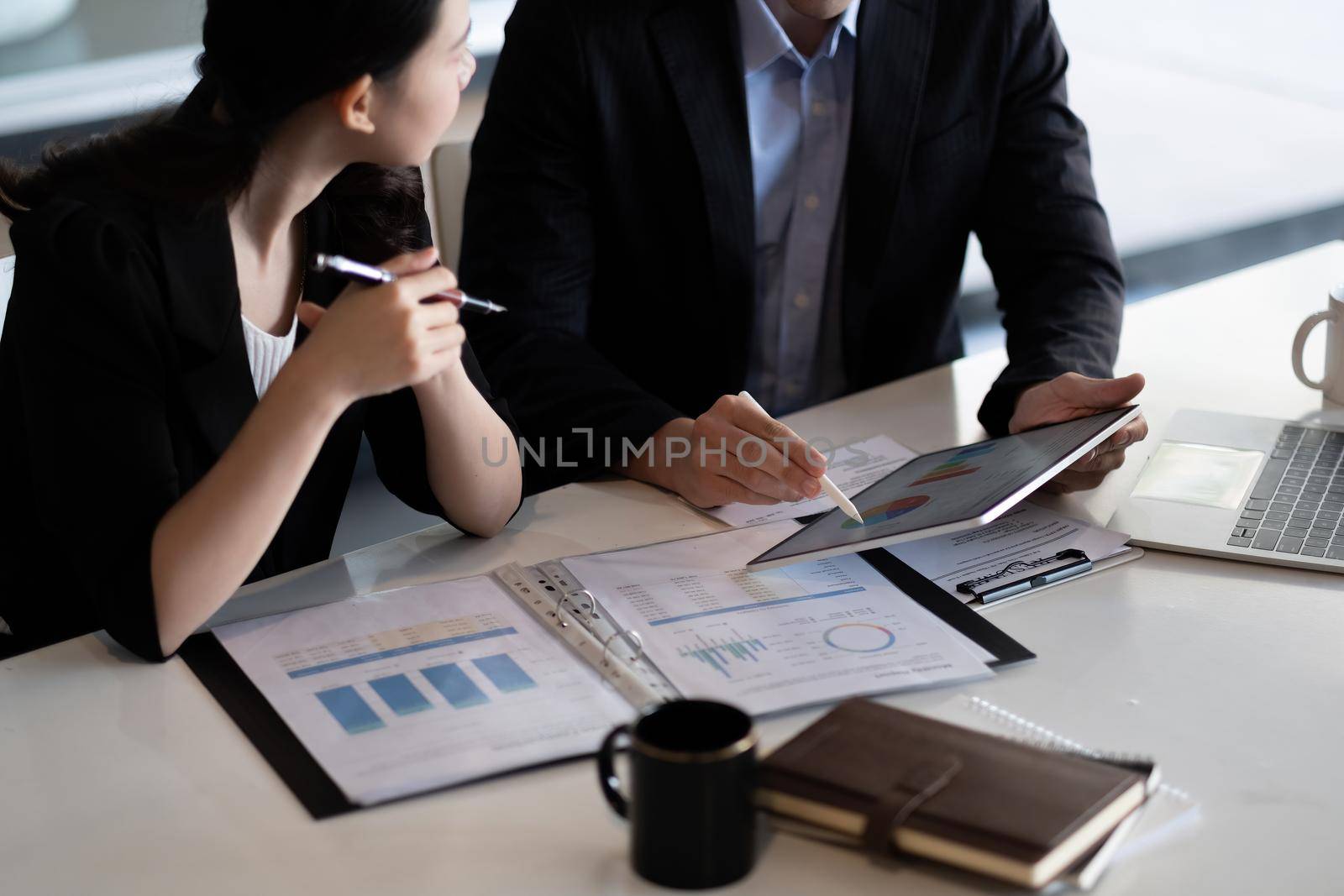 Close up of business people discussing a financial plan with paperwork and digital tablet by nateemee