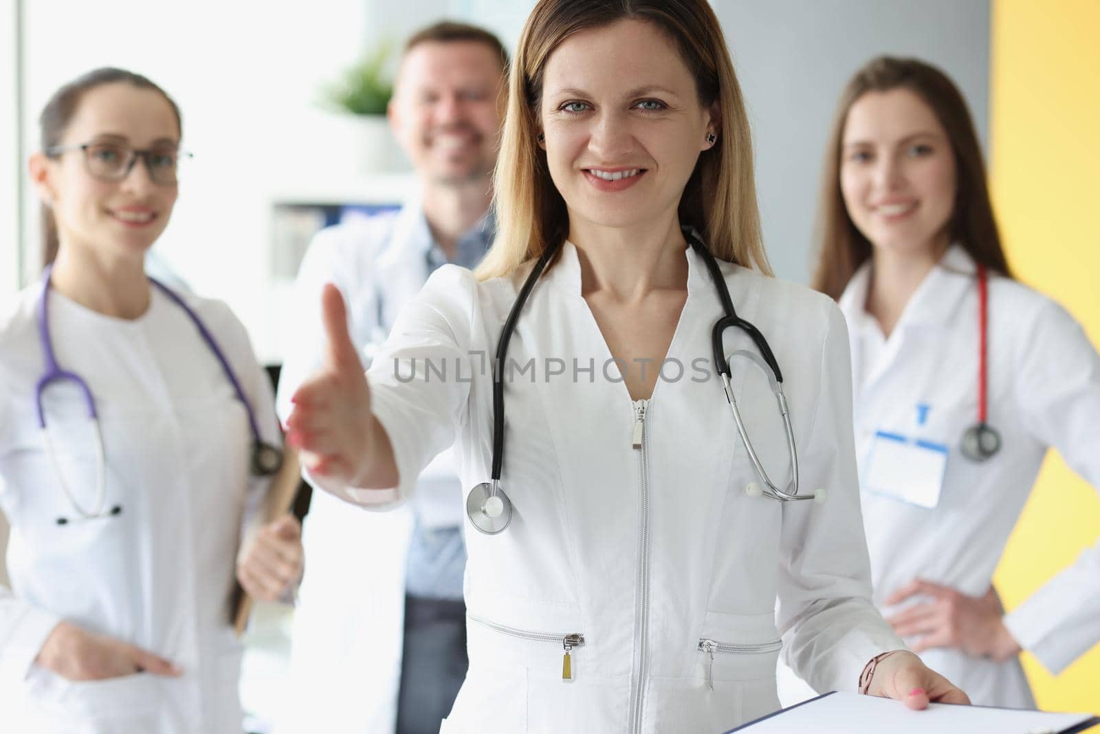 Friendly young woman doctor stretches out her hand, close-up. Consilium, medical staff of the clinic