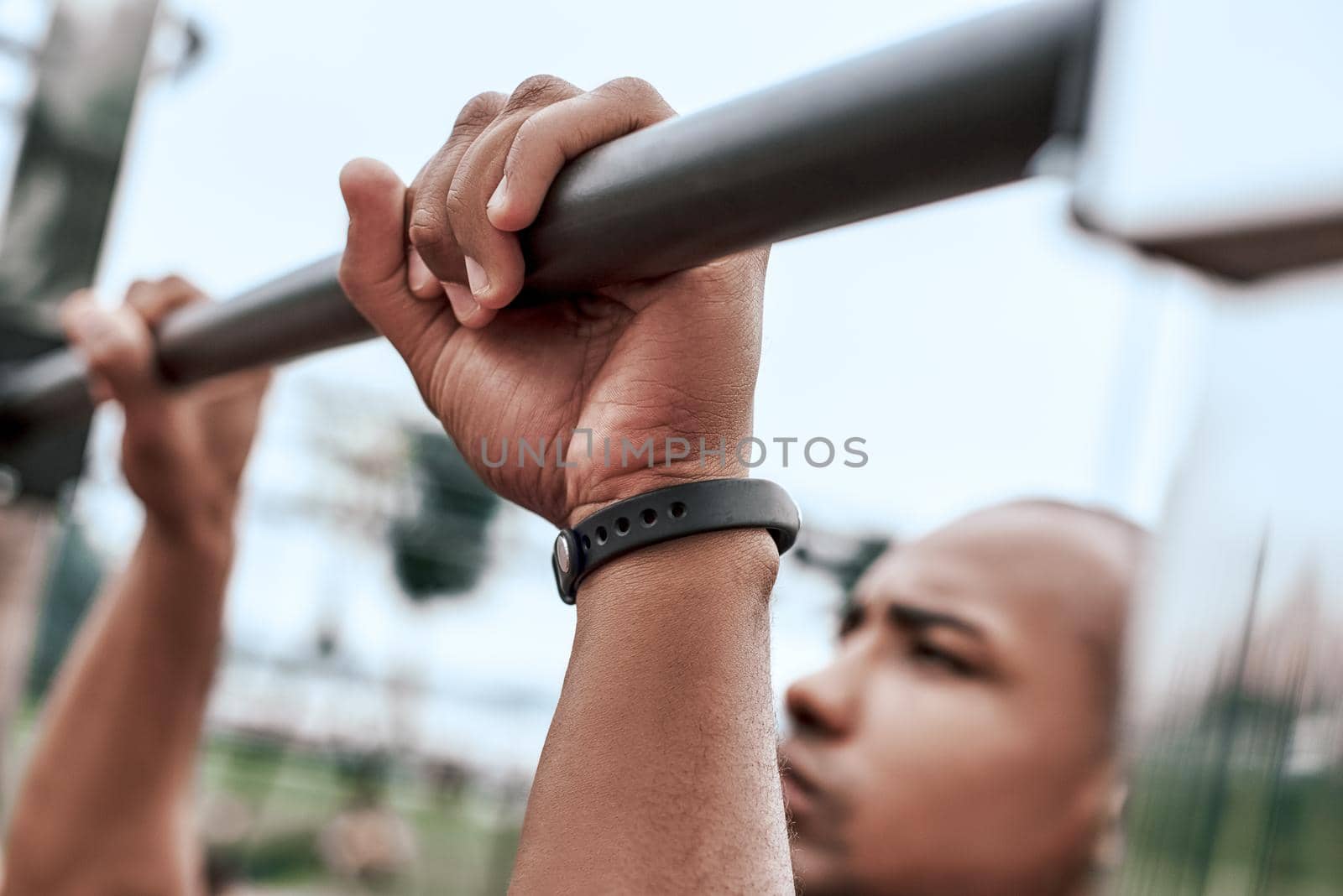 An african man is exercising at open air gym. Close-up cropped photo of black african handsome guy in sports clothes is doing exercises for his hands