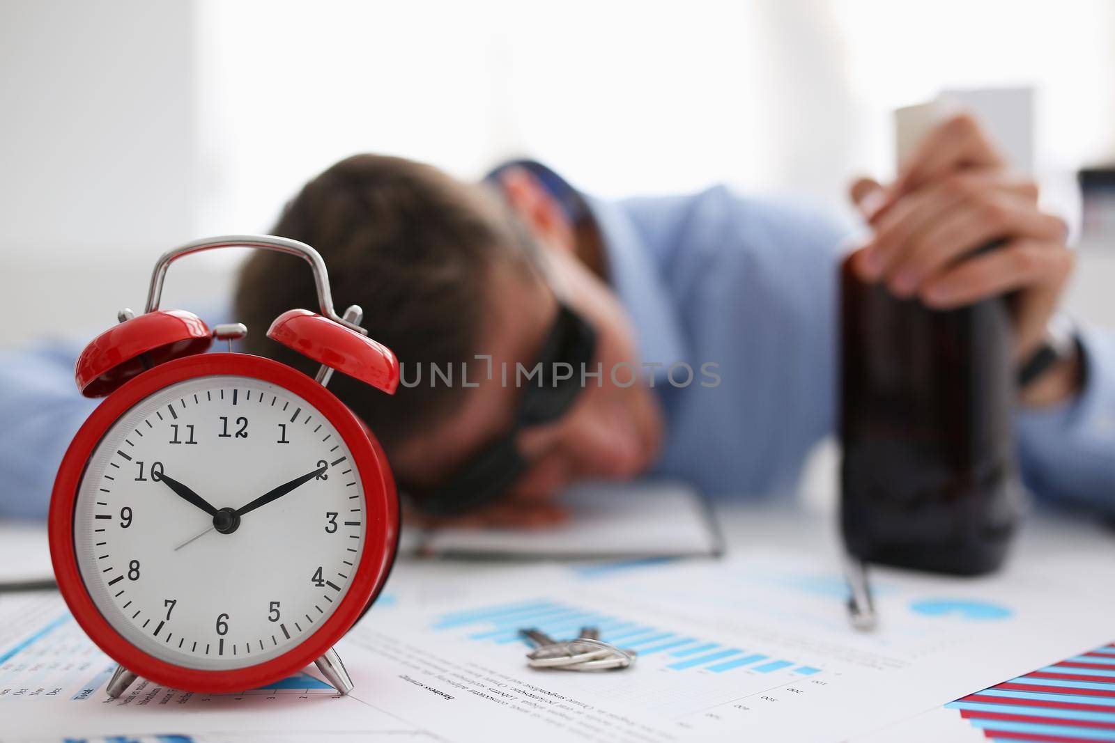 Businessman in blue shirt asleep at work on the background of a bottle of alcohol, overslept because stormy night party with a drink after corporate on January 1 celebrated new year very bad hangover