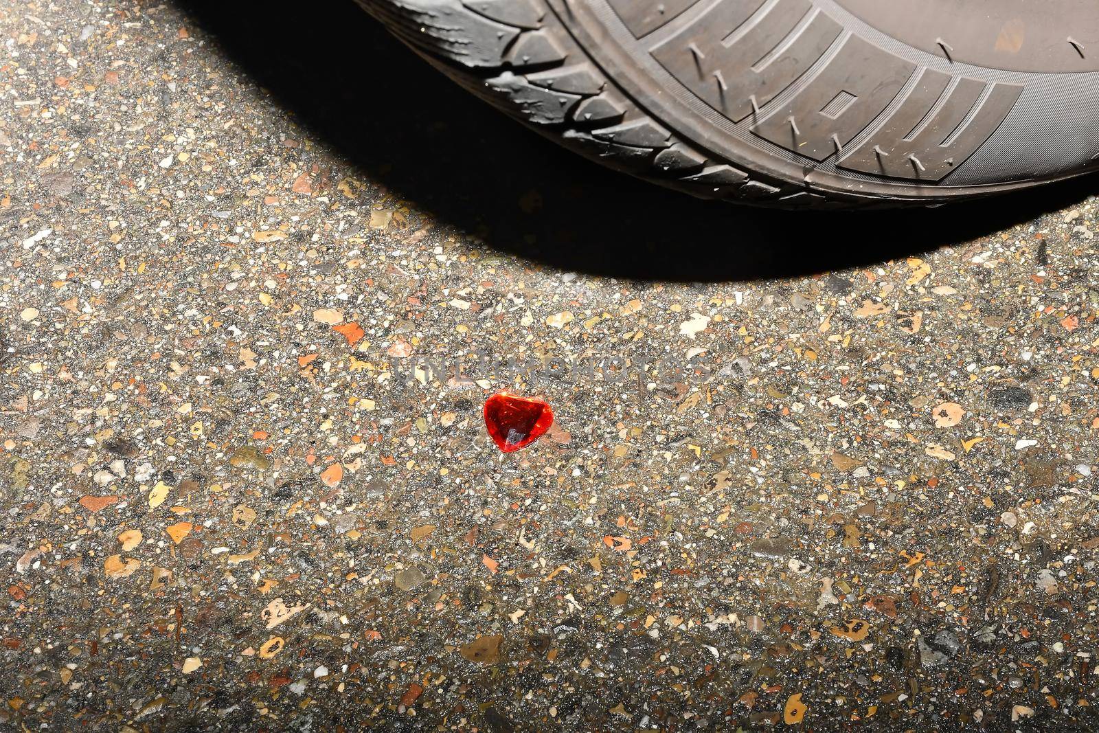 Heart on a road in front of a car wheel