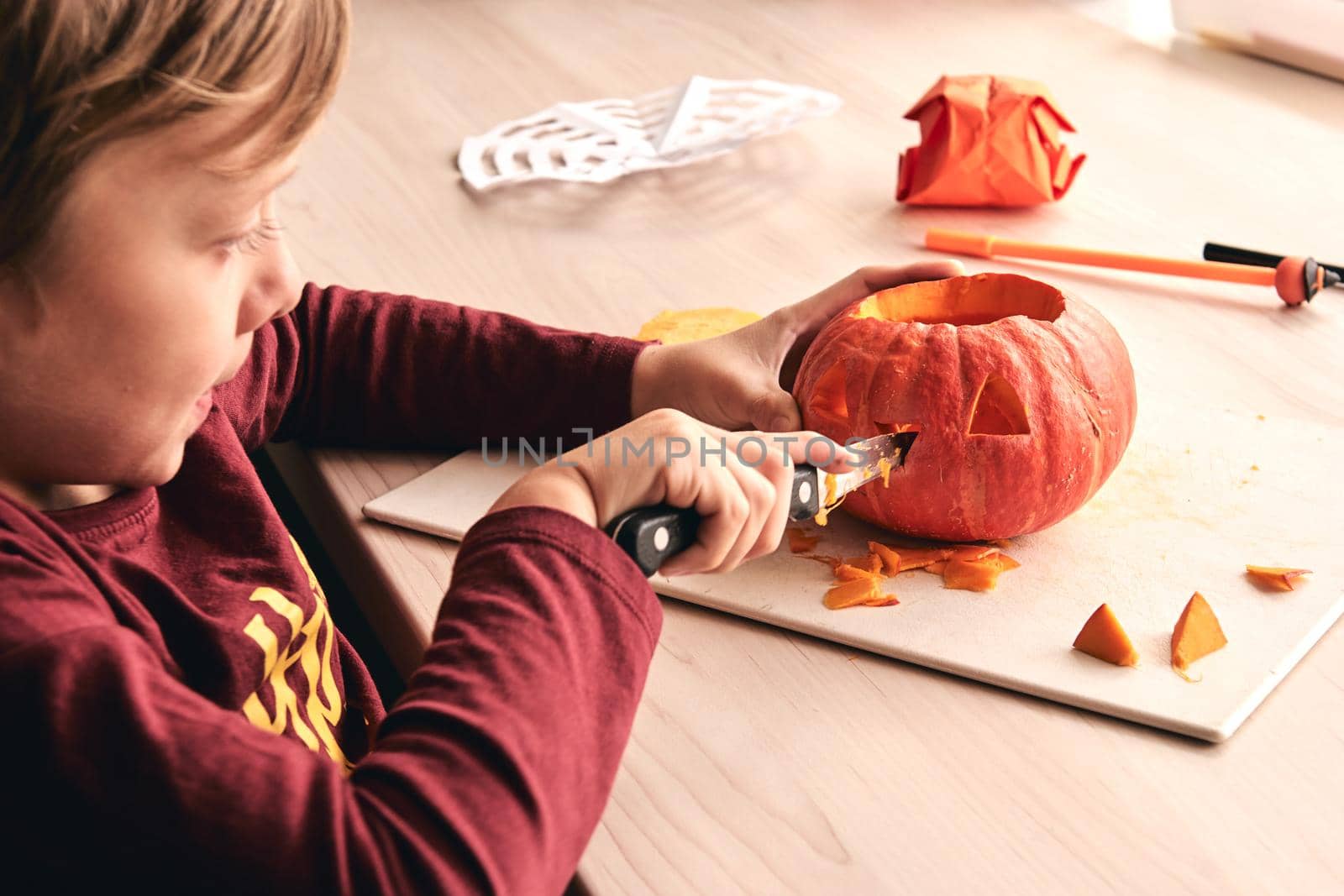 Halloween, decoration and holidays ideas- close up of kid with knife carving pumpkin or jack-o-lantern. 6 years boy has homefamily fun activity. Mom spending time with son together.