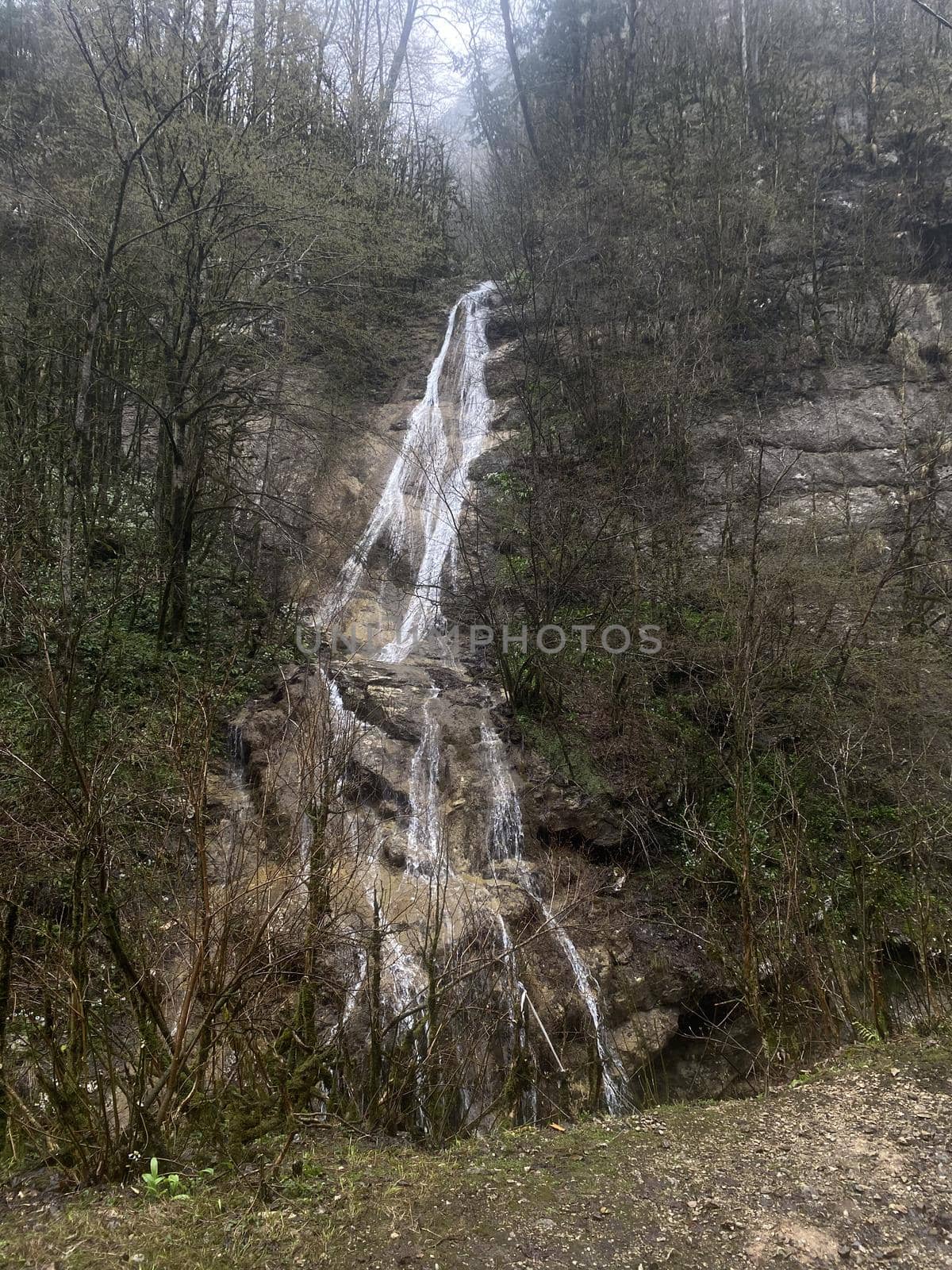 Beautiful landscape of small waterfall in cloudy weather. Clean waterway flowing down through mountainous terrain