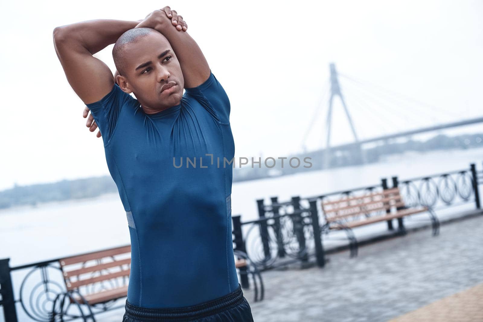 Young male jogger athlete training and doing workout outdoors in city.