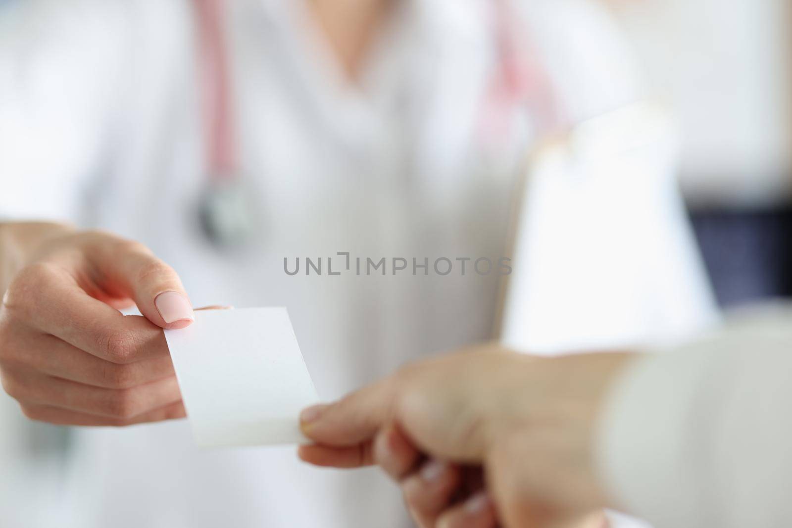 Doctor's hands hold out the document to the patient, mockup. Close-up of female hands. Receipt for payment of the service, prescription to the pharmacy