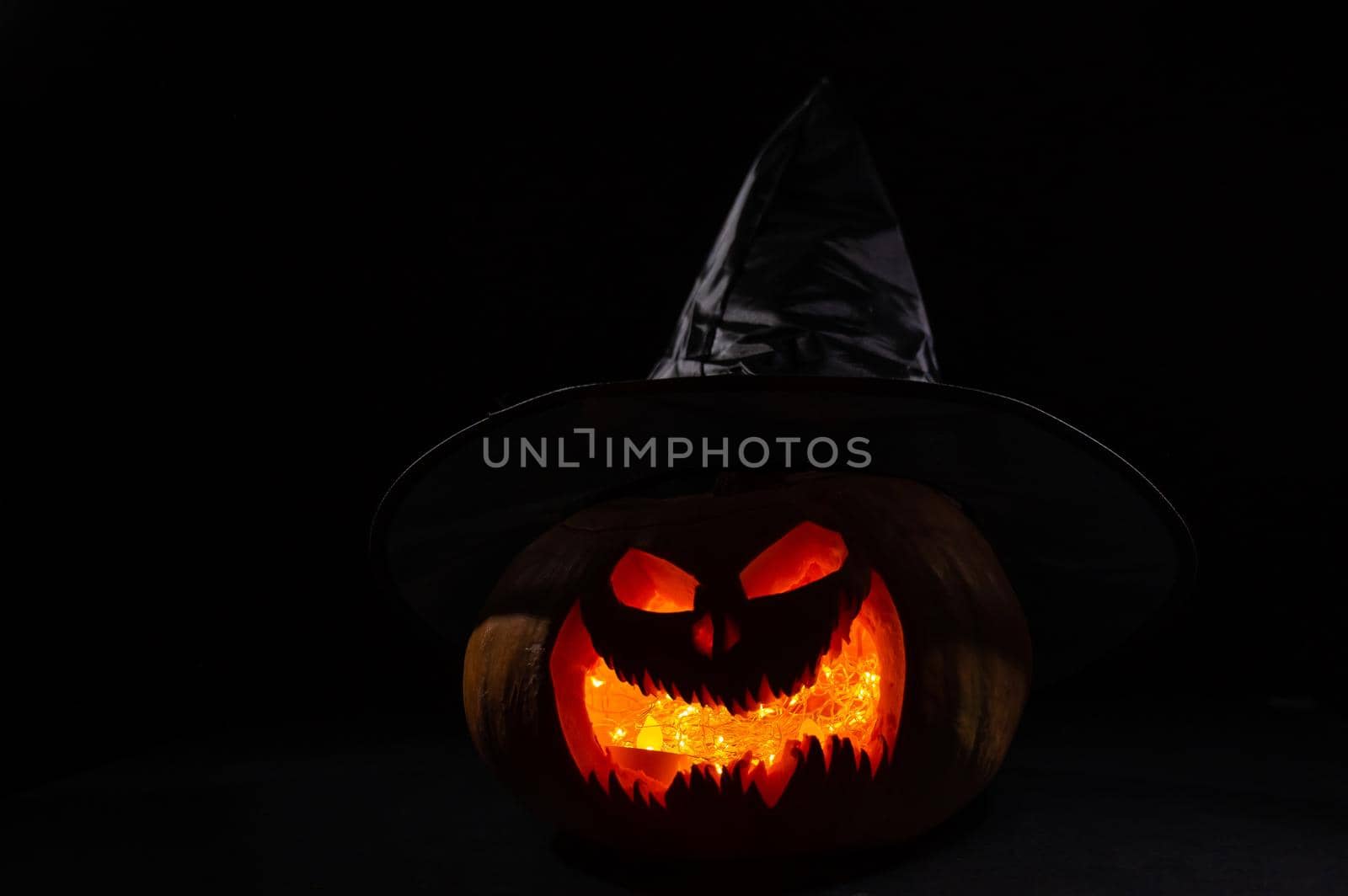 Glowing pumpkin in a witch hat in the dark. Jack o lantern