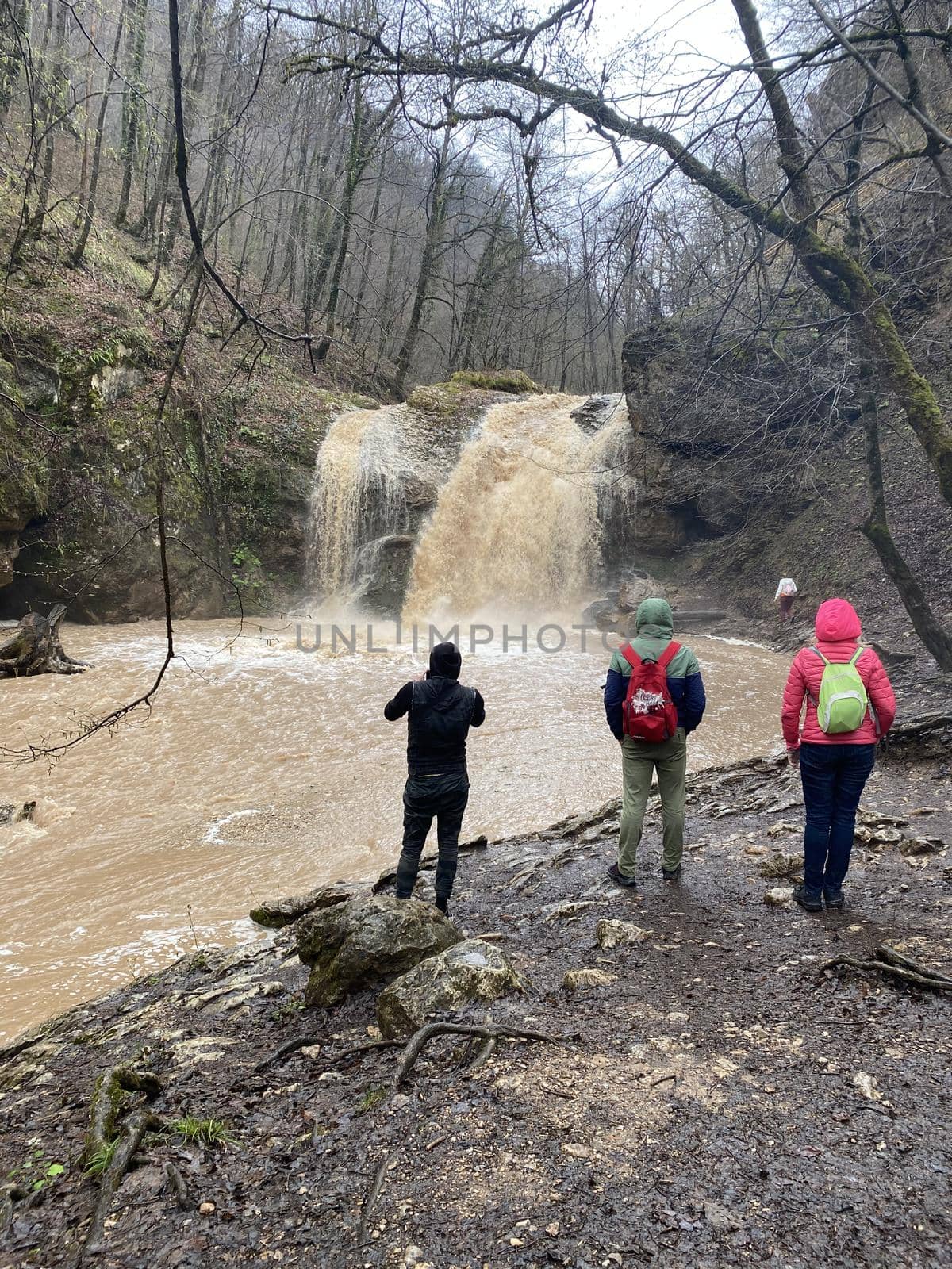 Guamka, Russia april 17, 2021: Beautiful landscape of powerful muddy waterfall in mountainous terrain. Dirty mountain waterway flows down and splashes. by epidemiks