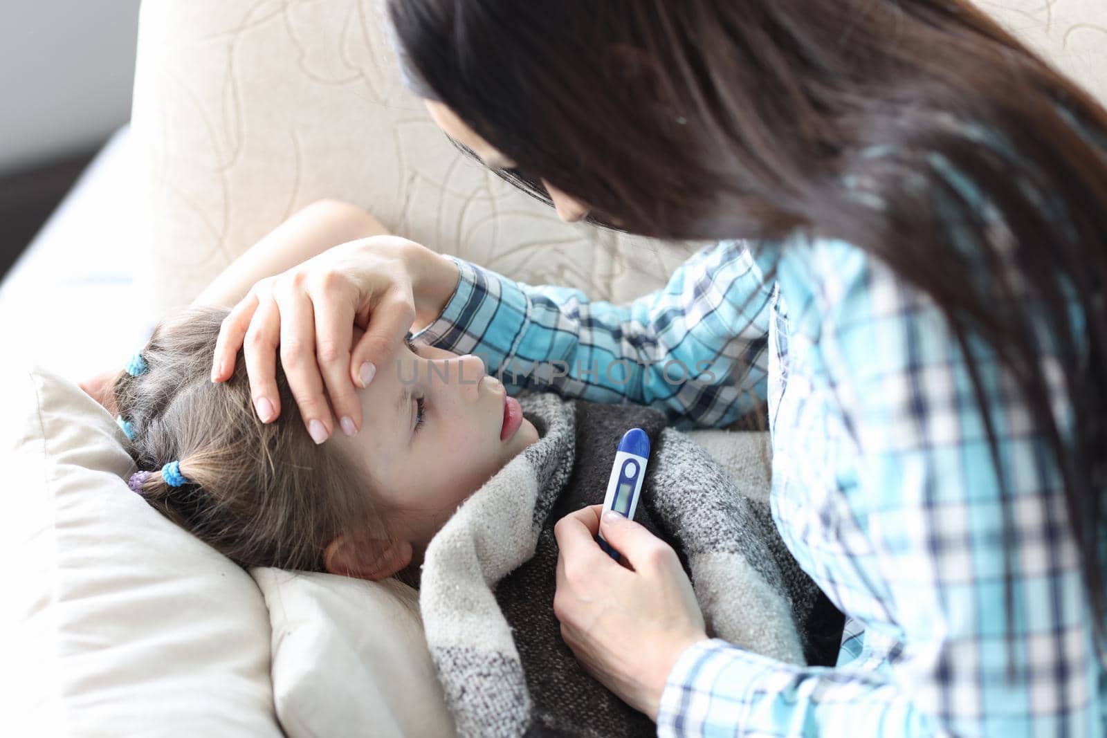 A caring mother touches the forehead of a sick girl by kuprevich