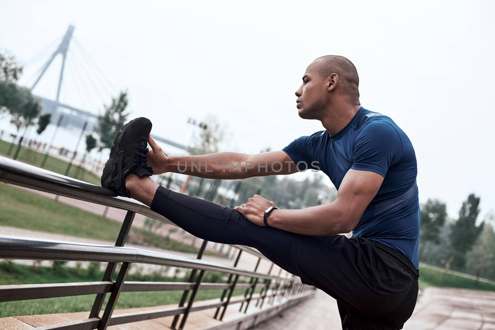 Side view portrait of an african sportive man who is stretching legs by friendsstock