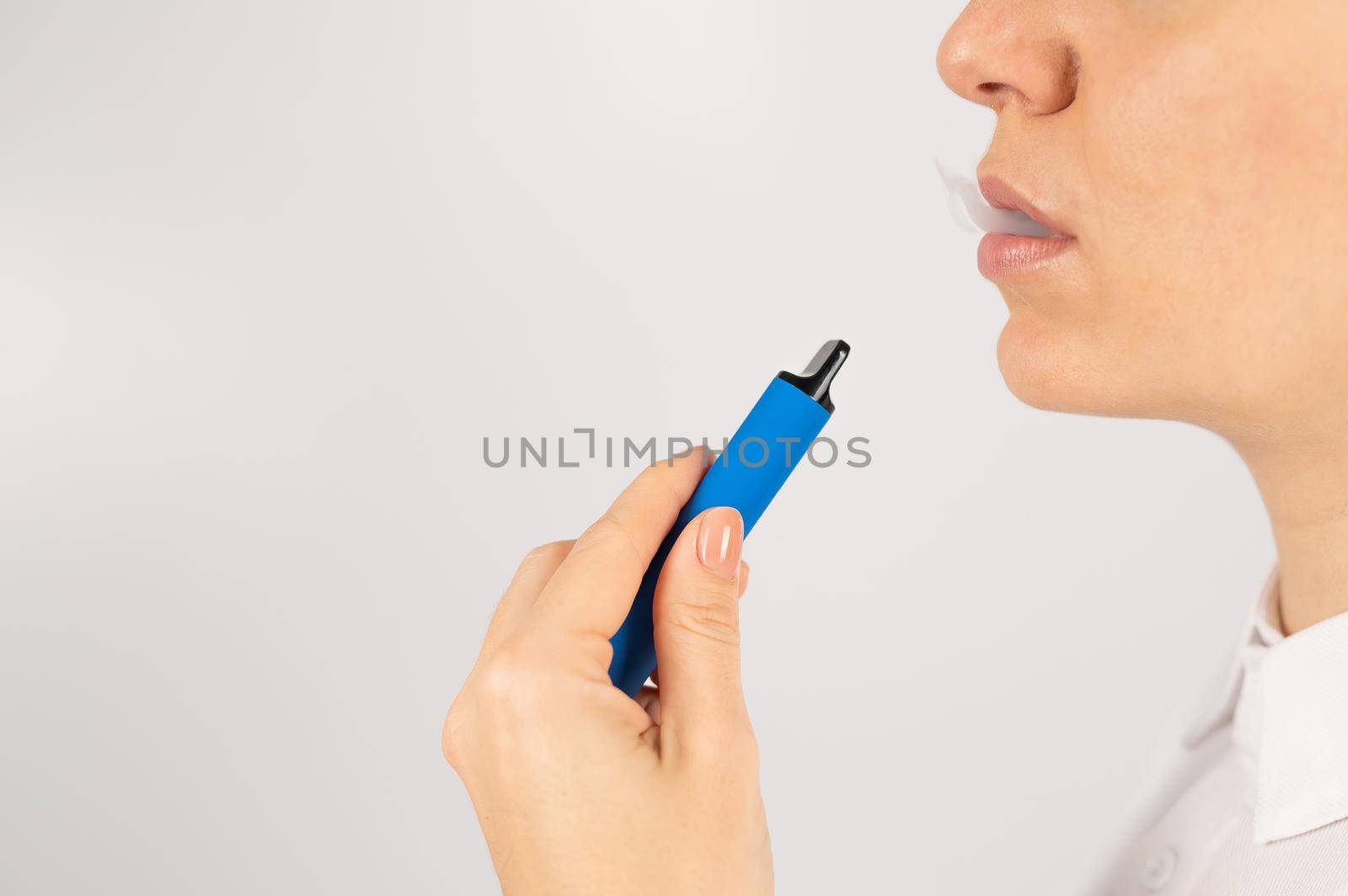 Caucasian woman smokes disposable vape on white background. Alternative device for smoking. by mrwed54