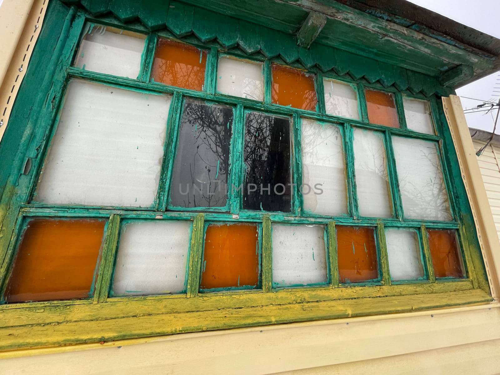 An old wooden window with multicolored panes. Multicolored glass panels on the antique window by epidemiks