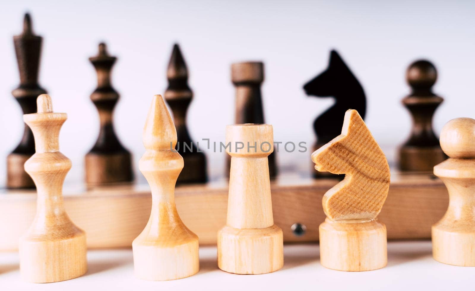 White and black wooden pieces on a chessboard. A chessboard set up during a game on a gray background