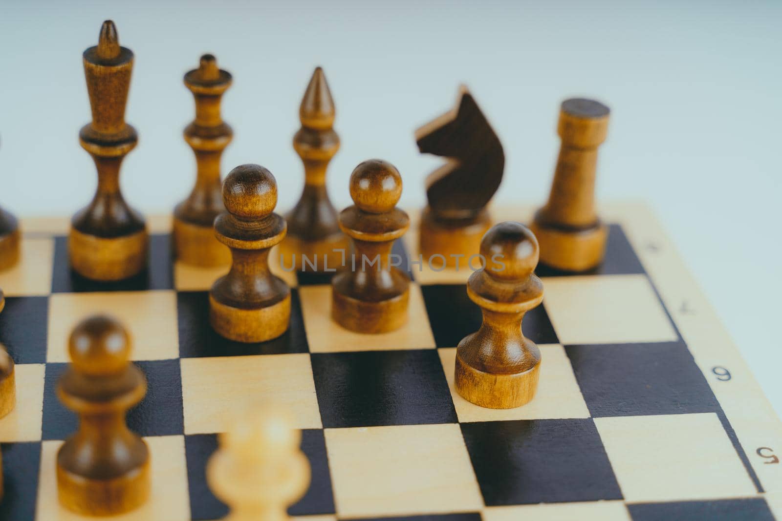 White and black wooden pieces on a chessboard. A chessboard set up during a game on a white background