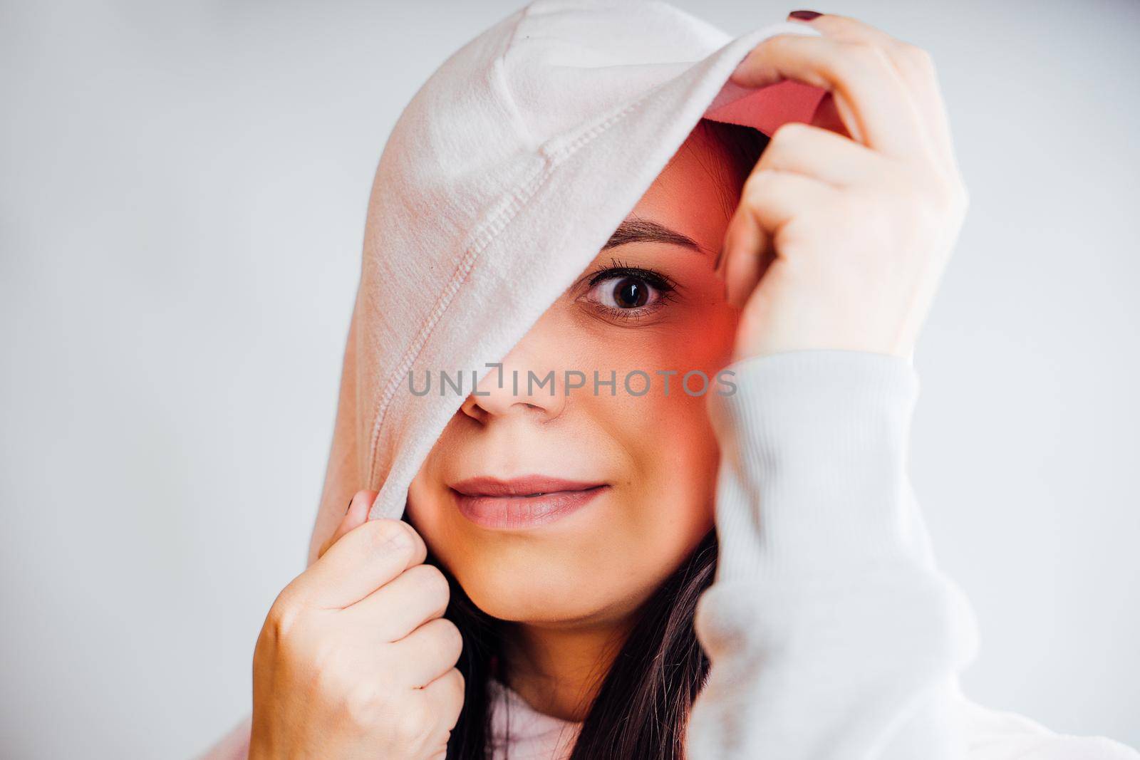 The woman hides her face behind the hood. Stylish female posing in a hoodie. Portrait of a young woman covering her face with a hood by epidemiks