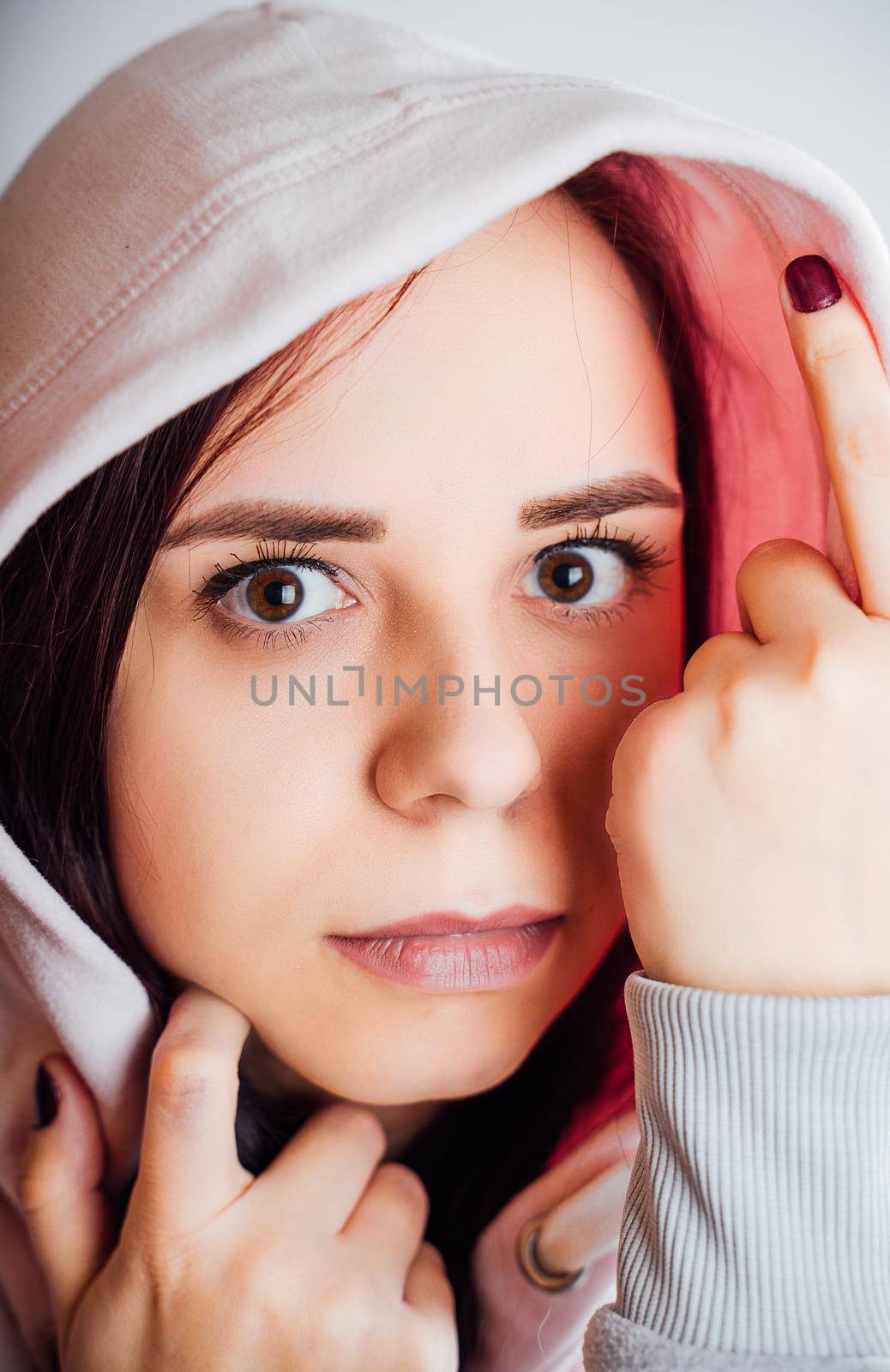 Portrait of young woman looking at camera. Close up of pretty female in hood. by epidemiks