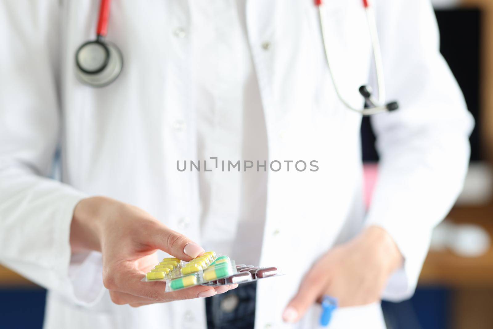 A female doctor in uniform holds capsules in a blister in her hands. Pharmaceft in the pharmacy offers bio food supplements