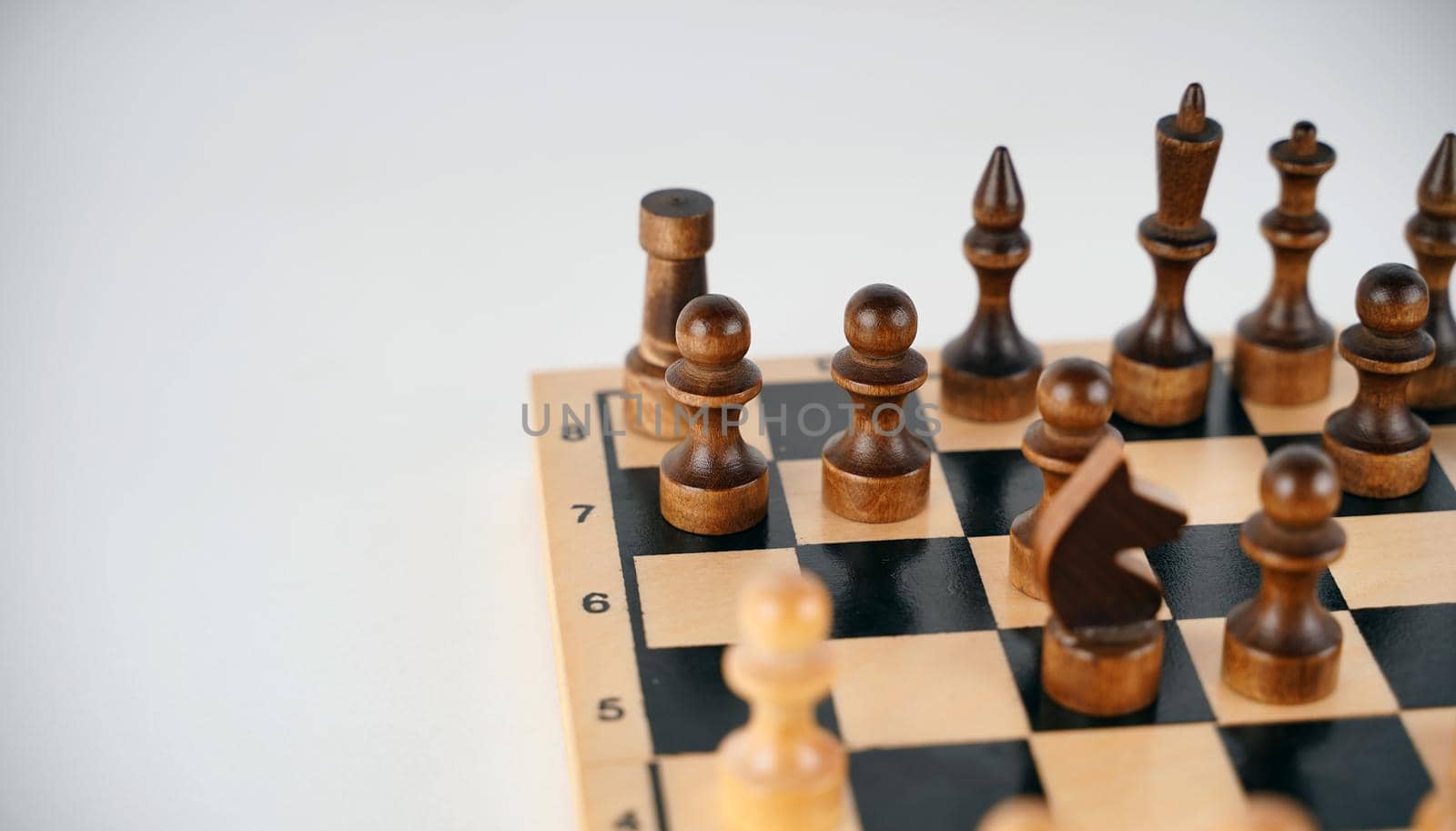 White and black wooden pieces on a chessboard. A chessboard set up during a game on a white background. by epidemiks