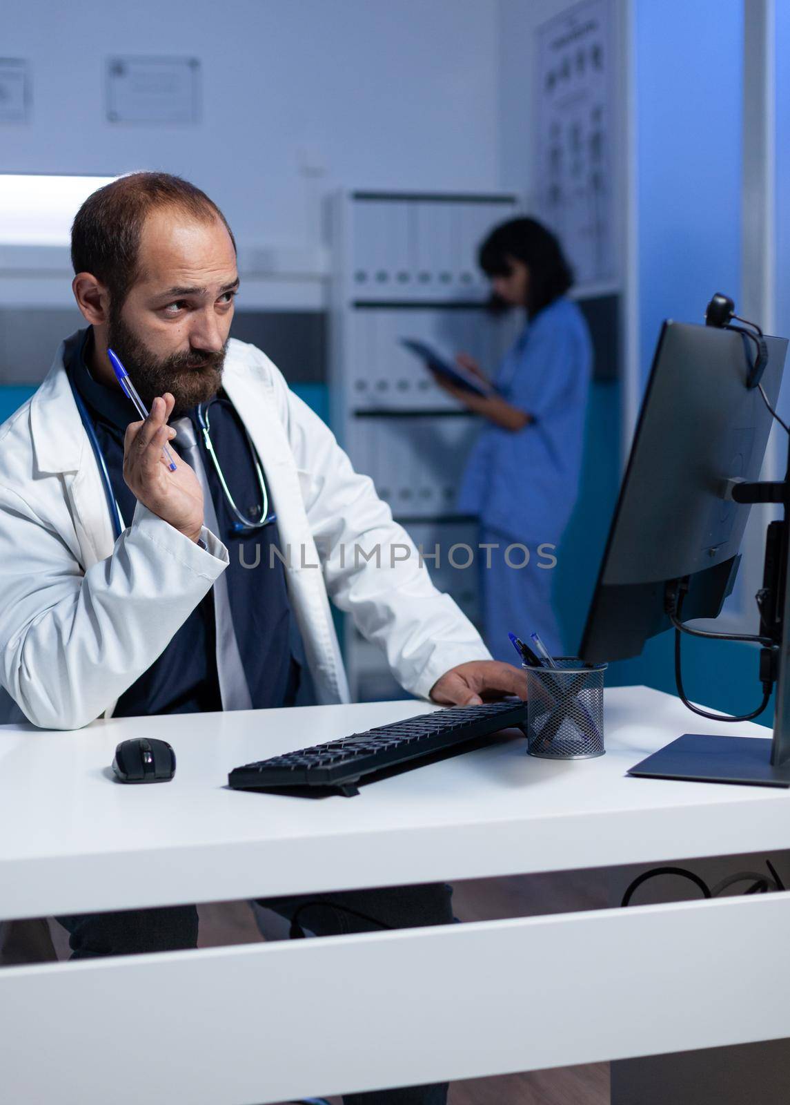 Doctor using video call on computer for remote communication, working late at office. Medic talking to patient on online video conference for emergency telehealth consultation at night.