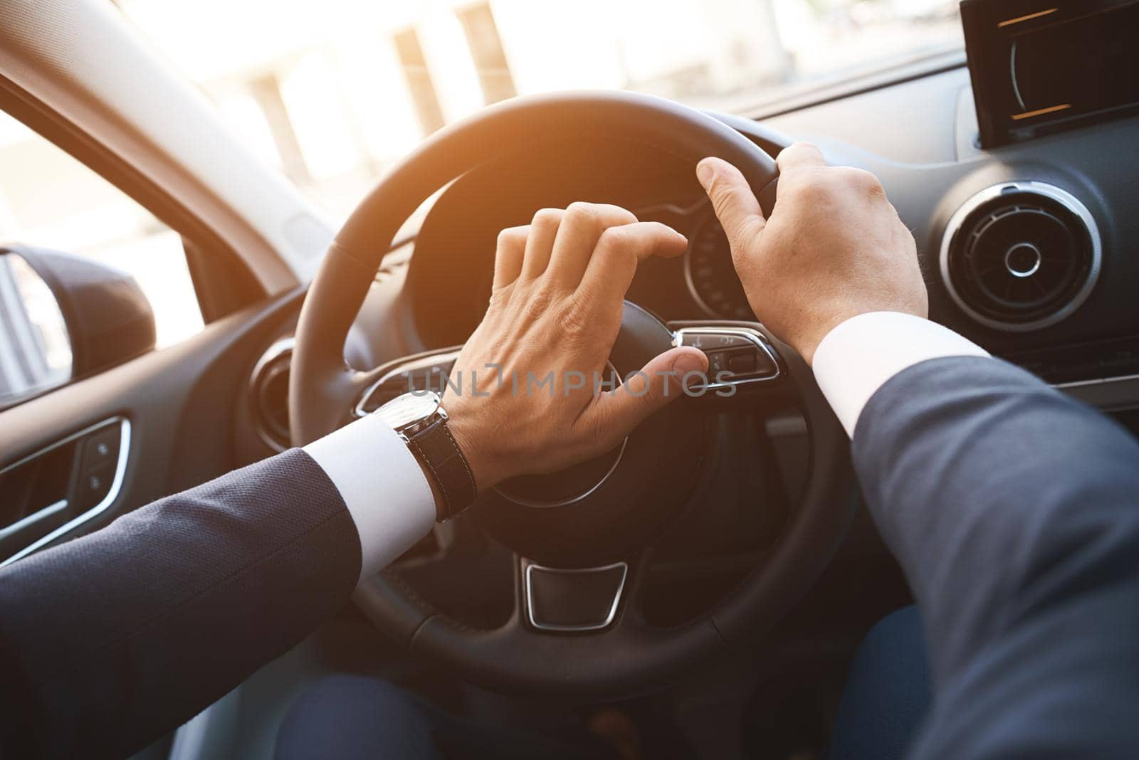 Close-up of a man driving a car with a hand on a horn button. Sunset filter by friendsstock