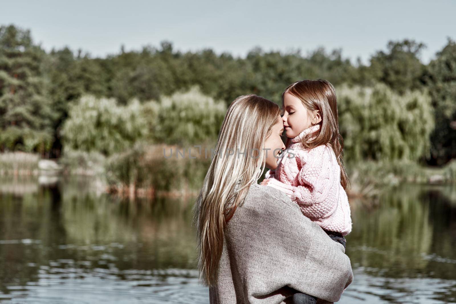 Happy, girl kisses her beautiful mother near lake, close-up by friendsstock