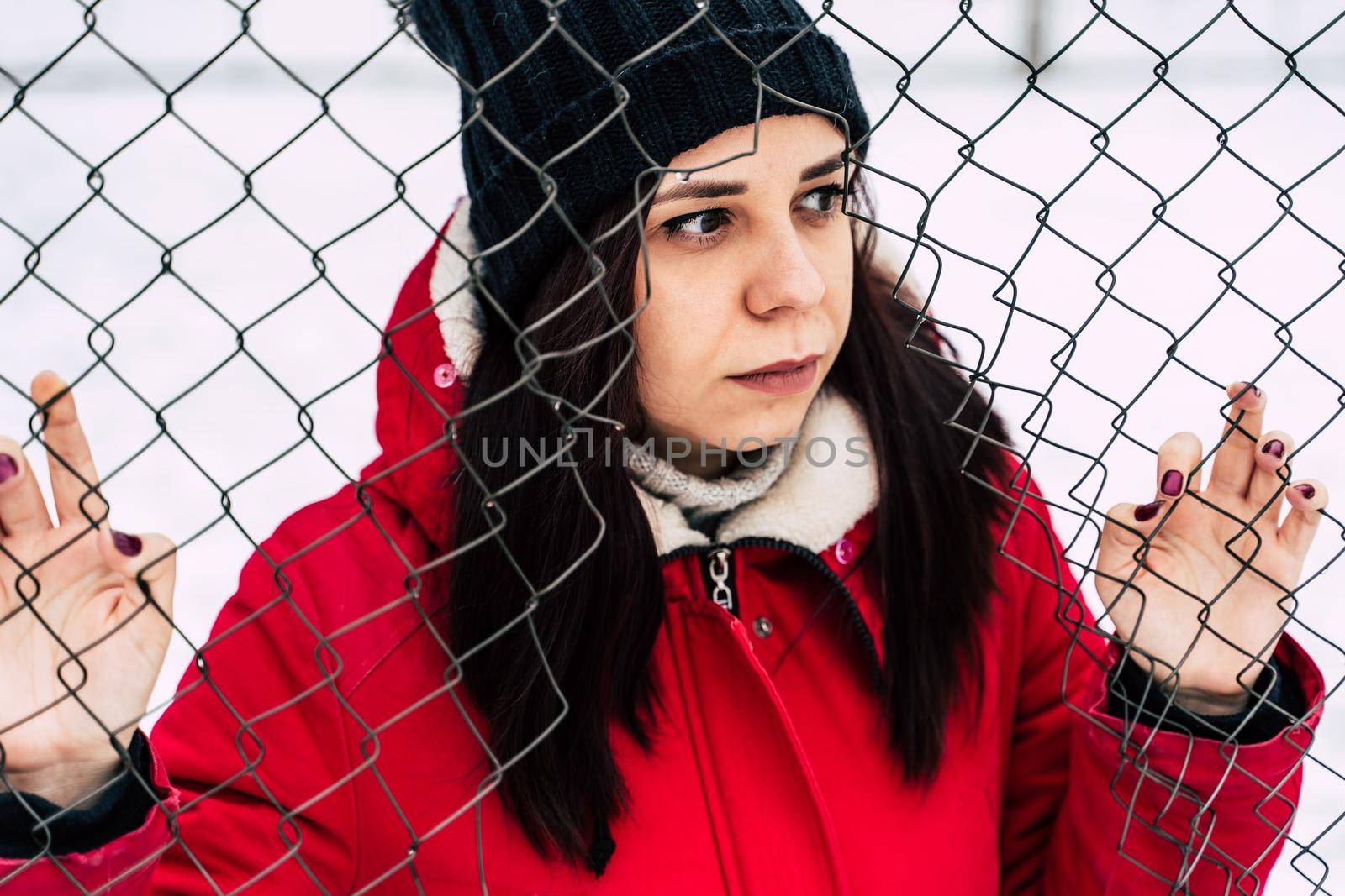 beautiful young girl in a red jacket posing outside during winter day.