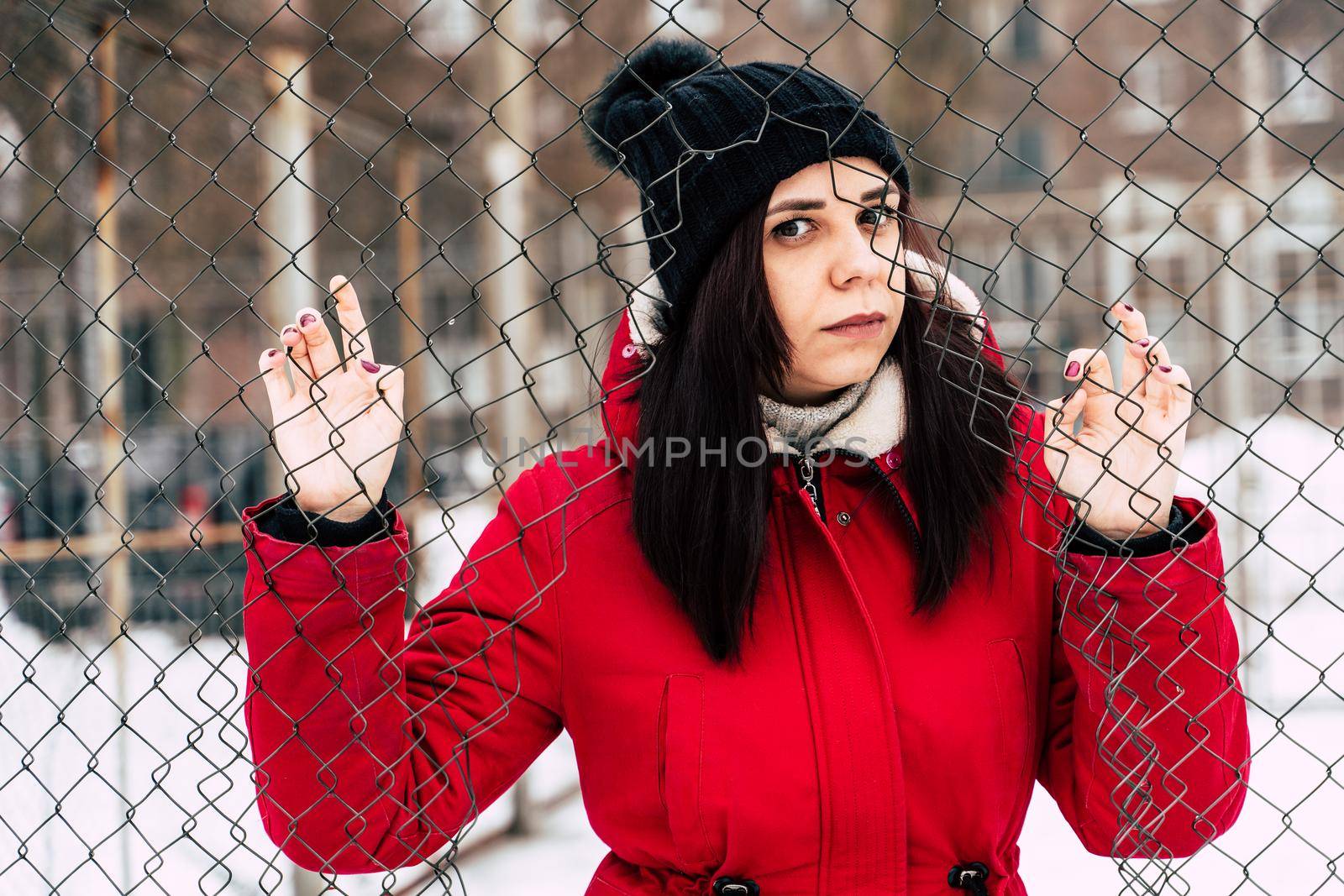 beautiful young girl in a red jacket posing outside during winter day.