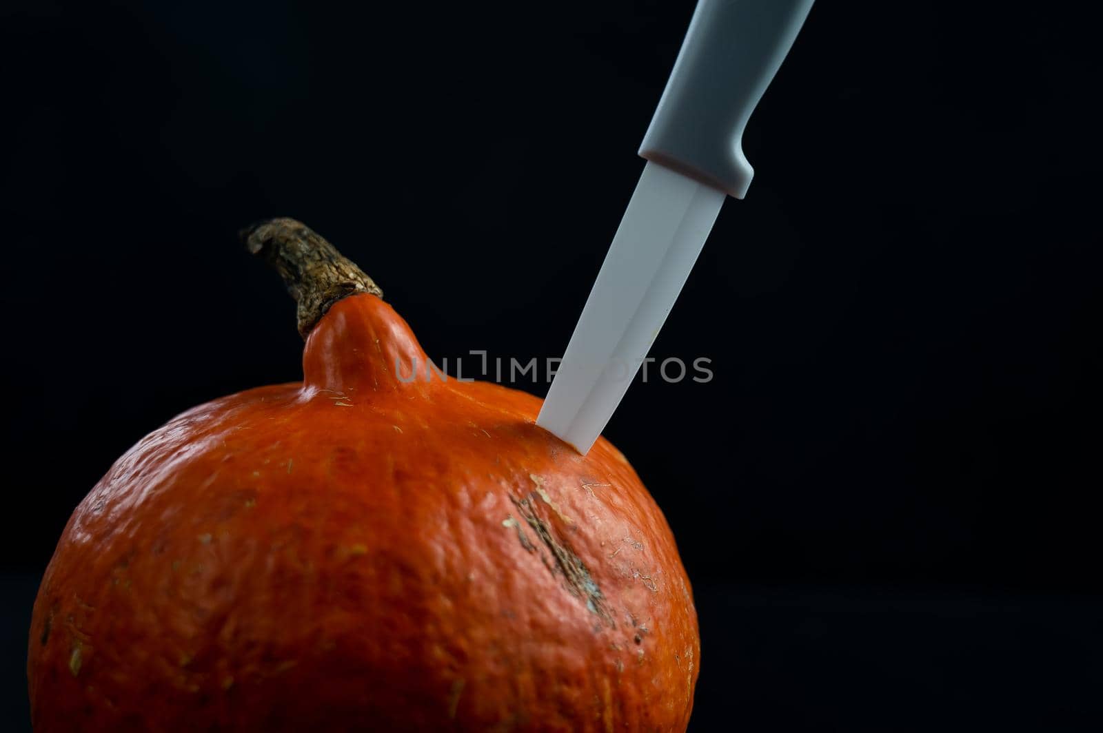 Knife in a pumpkin on a black background. Halloween symbol. Isolate