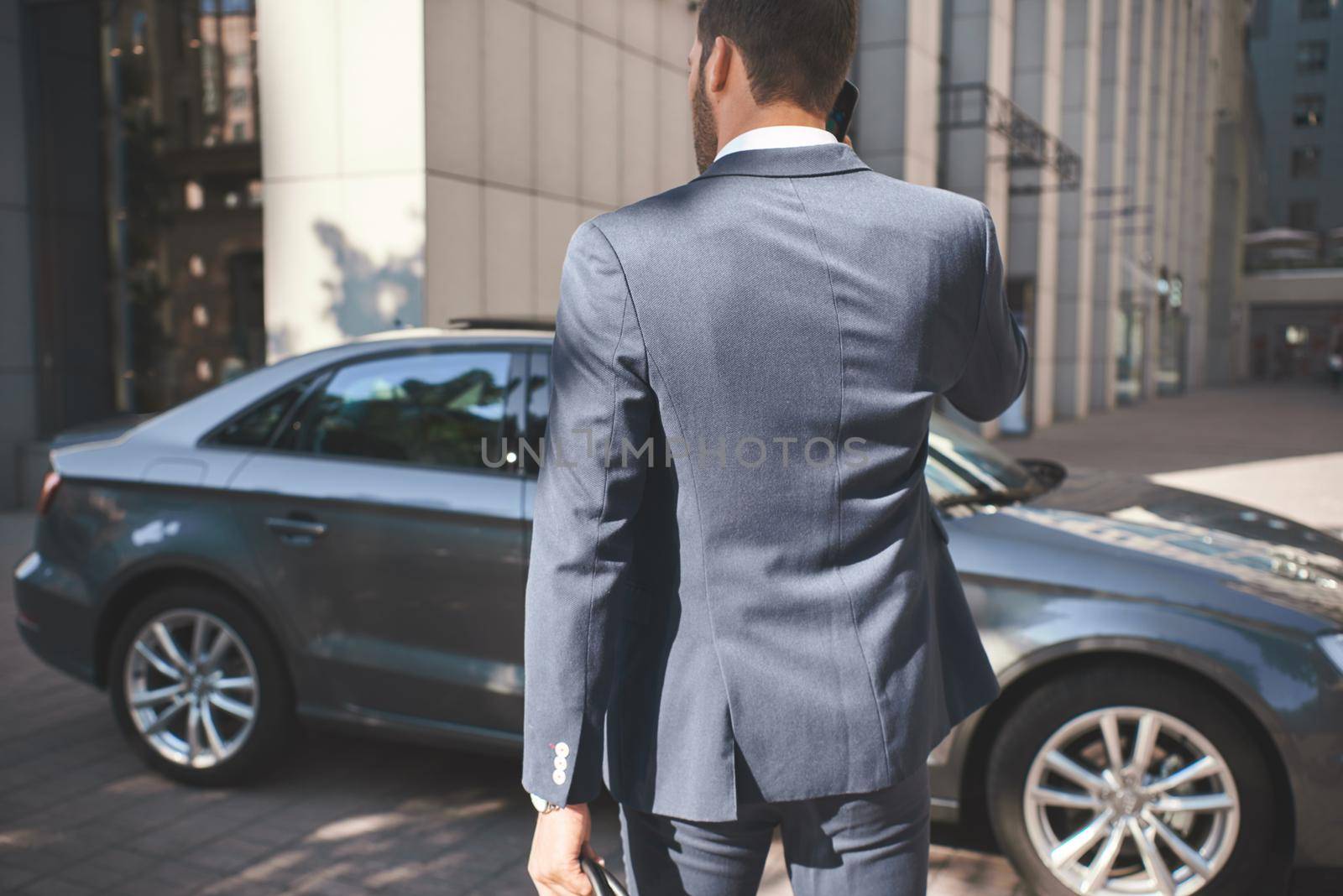 Confident businessman. Young businessman comes to car by friendsstock