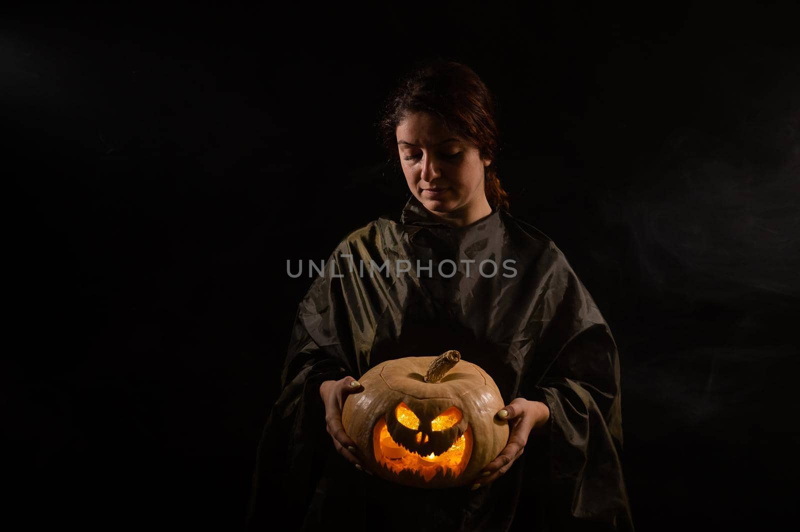 Caucasian woman holding pumpkin in the dark.