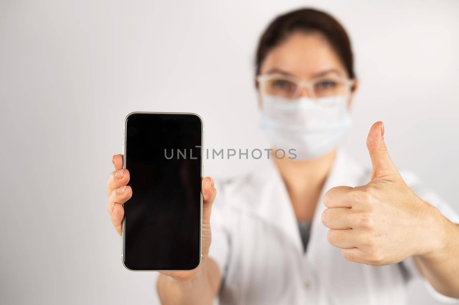 The doctor holds a smartphone with a black screen on a white background