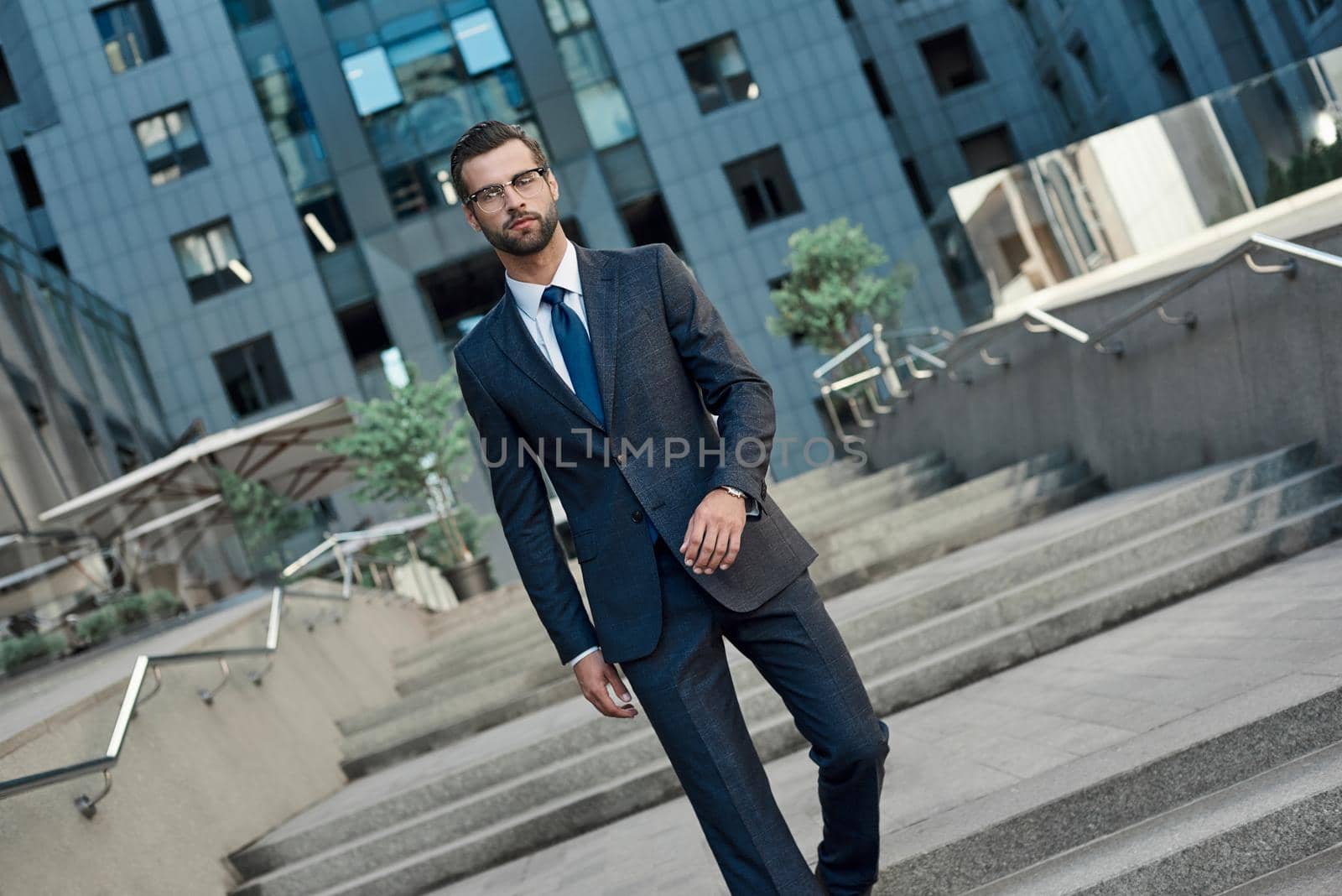 Young businessman with glasses and a beard descends the stairs by friendsstock