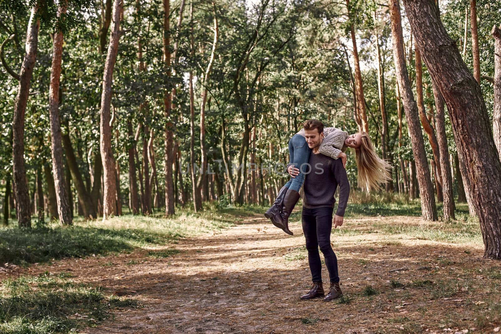 Outdoor happy couple in love posing in autumn forest. Young woman and man having fun outdoor