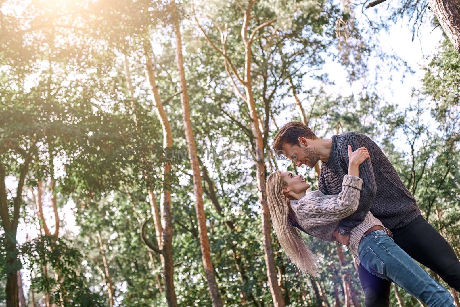Outdoor happy couple in love posing in autumn forest. Young woman and man are dancing outdoor