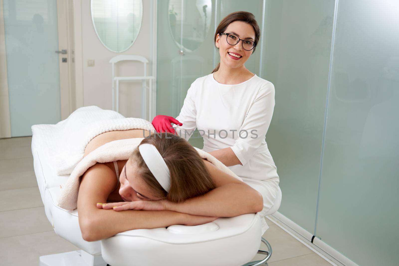 Young woman getting fat reductive skin lifting body treatment by cosmetologist. Attractive female patient enjoying slimming body contouring procedure