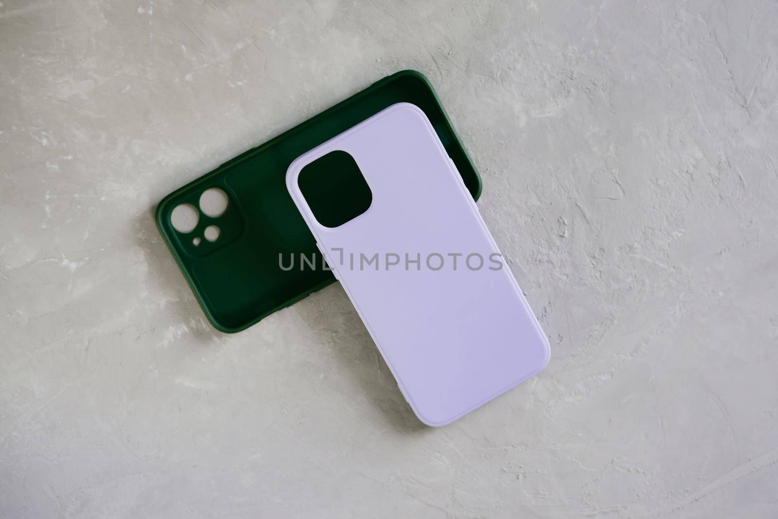 Purple and green smartphone cases. Two silicone cases on a textured gray background.