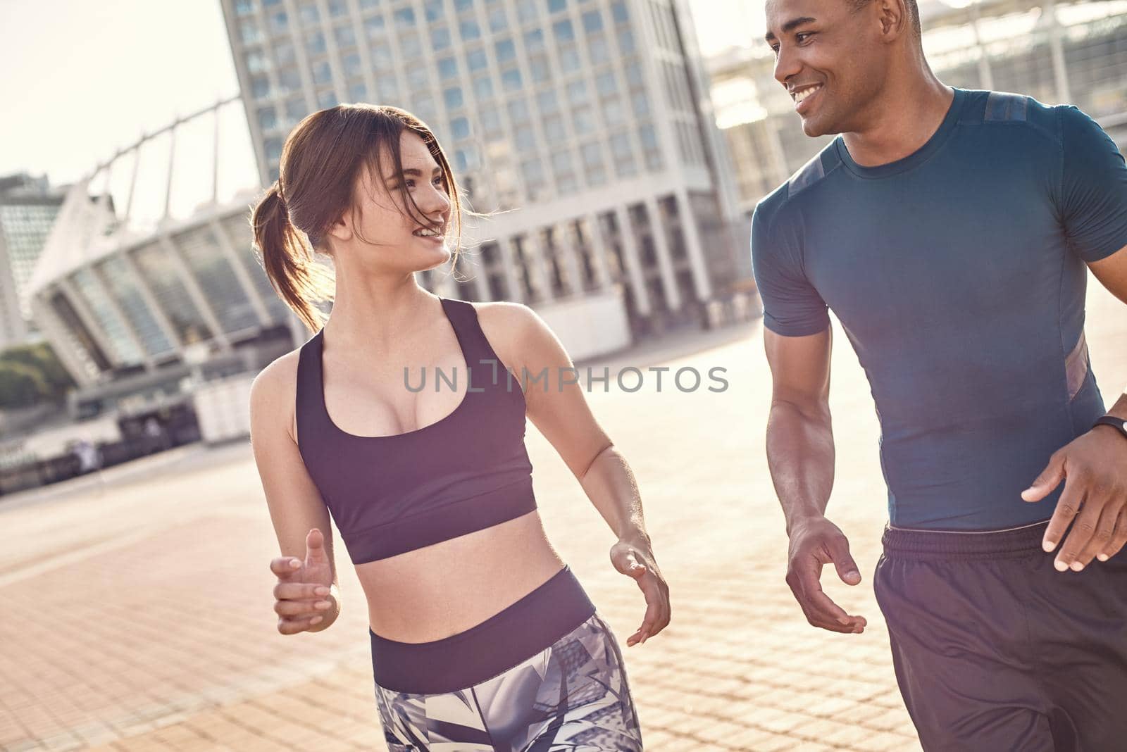 Common hobbies. Young and happy multiracial couple running across sunny streets in the morning. Healthy couple. Sport motivation concept. Fitness concept. Women beauty. Healthy life. Exercising together